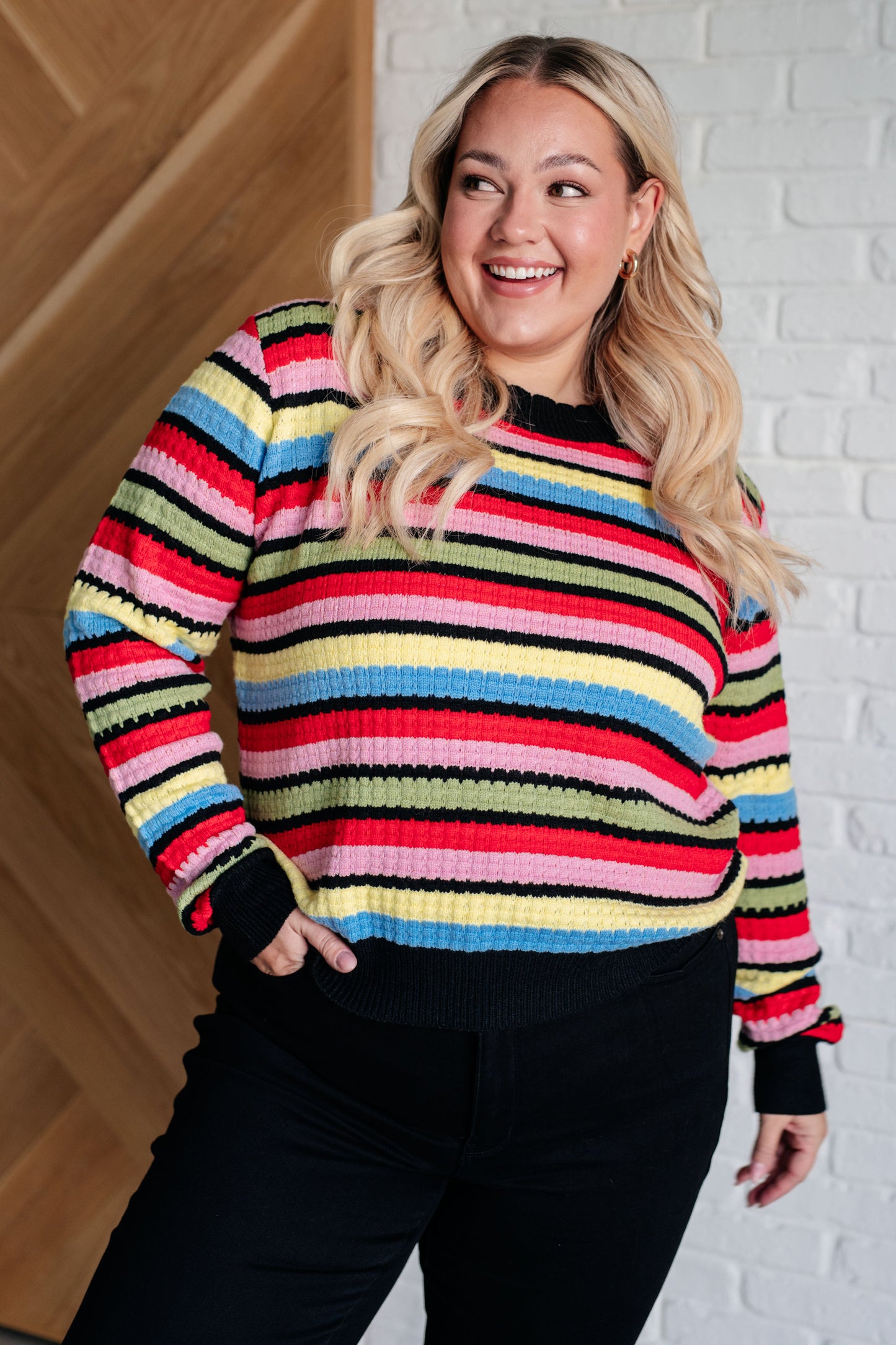 A women's striped sweater made of textured mid-weight knit fabric, featuring a crew neckline, long sleeves, and a comfortable fit. stripes of red, pink, blue, green, black, and yellow.