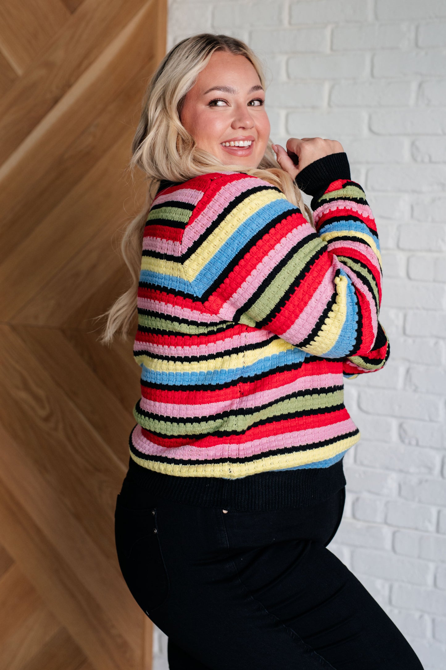 A women's striped sweater made of textured mid-weight knit fabric, featuring a crew neckline, long sleeves, and a comfortable fit. stripes of red, pink, blue, green, black, and yellow.