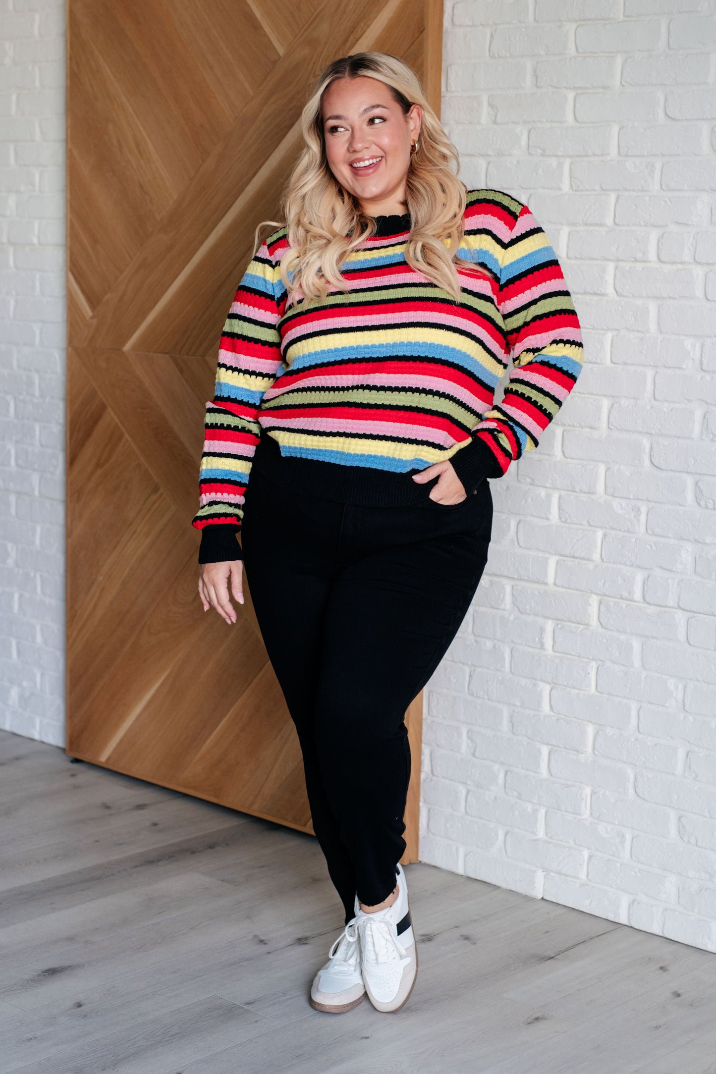 A women's striped sweater made of textured mid-weight knit fabric, featuring a crew neckline, long sleeves, and a comfortable fit. stripes of red, pink, blue, green, black, and yellow.