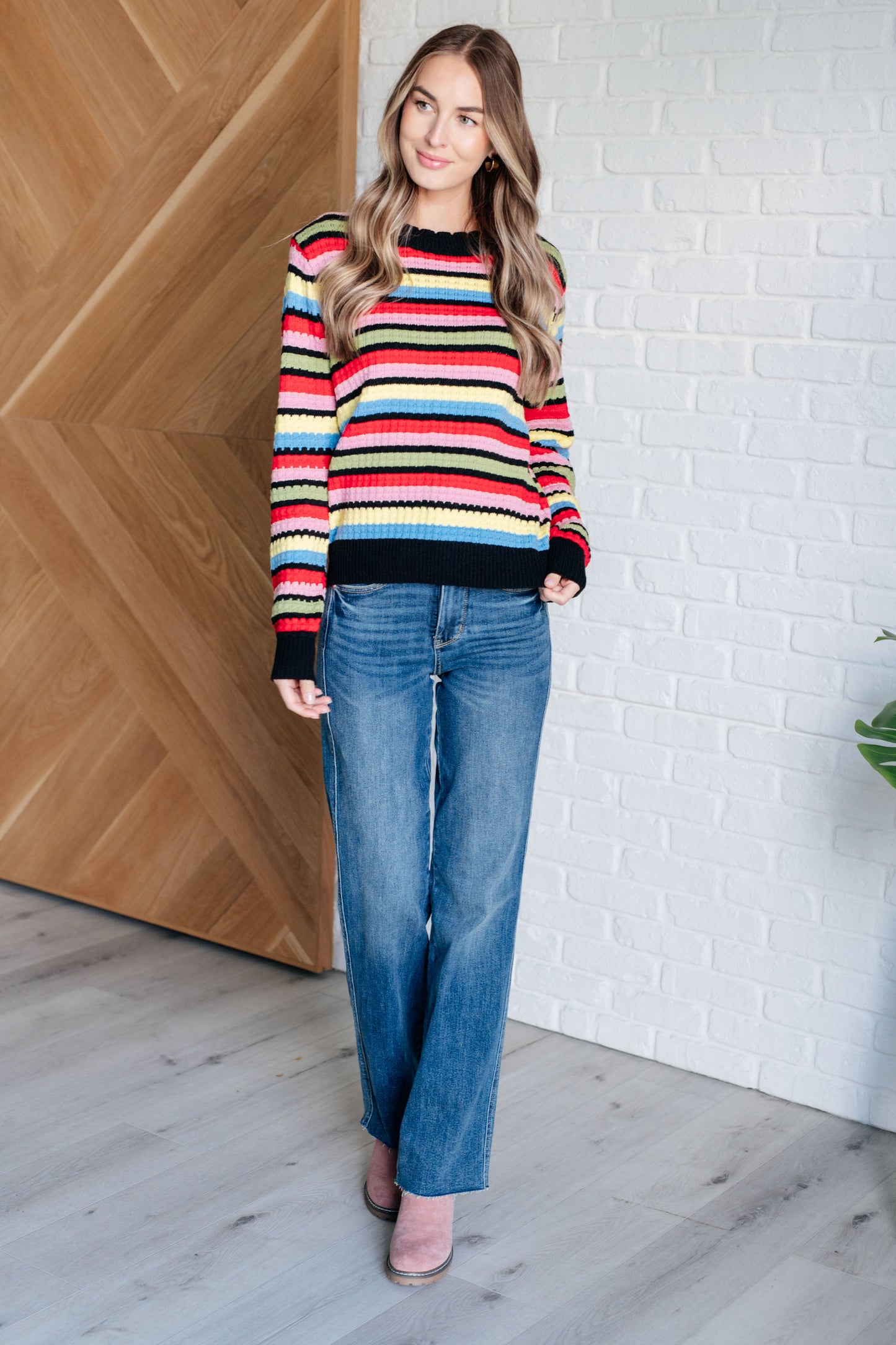 A women's striped sweater made of textured mid-weight knit fabric, featuring a crew neckline, long sleeves, and a comfortable fit. stripes of red, pink, blue, green, black, and yellow.