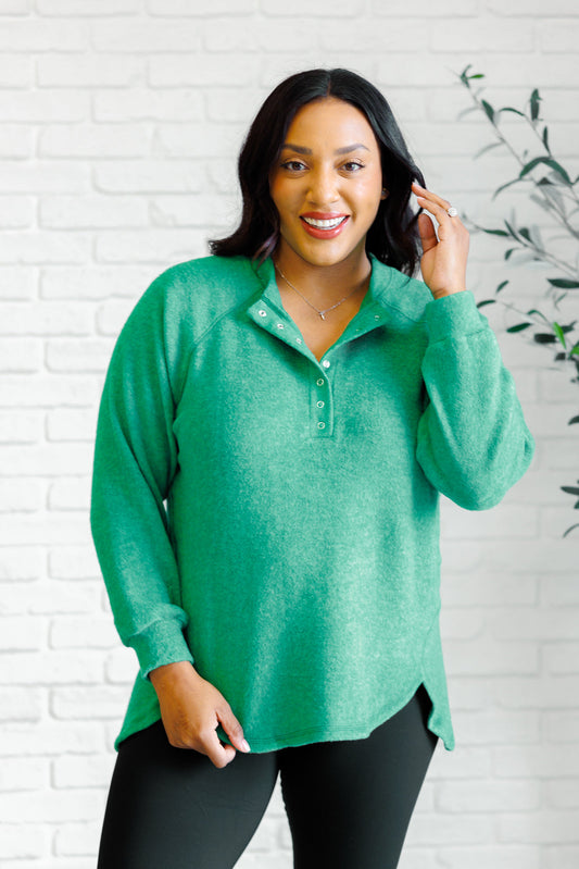 Forest green long-sleeve tee made from soft melange hacci knit fabric. Features a round neckline with half-snap buttons, raglan sleeves, and banded cuffs.