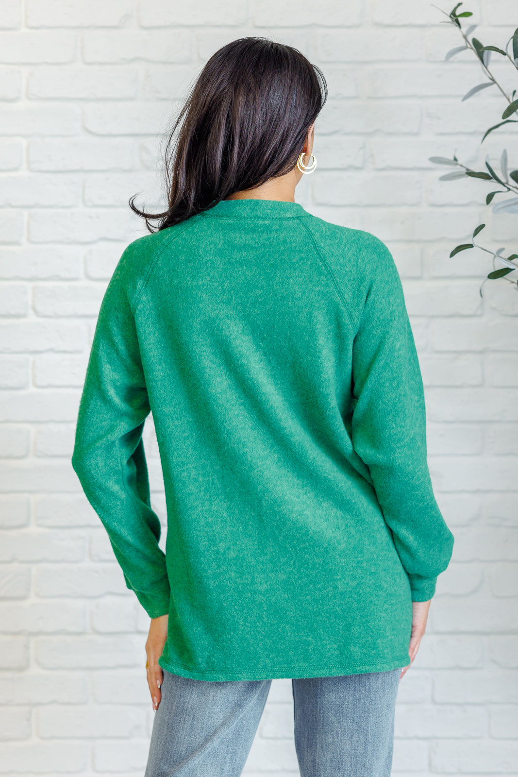 Forest green long-sleeve tee made from soft melange hacci knit fabric. Features a round neckline with half-snap buttons, raglan sleeves, and banded cuffs.