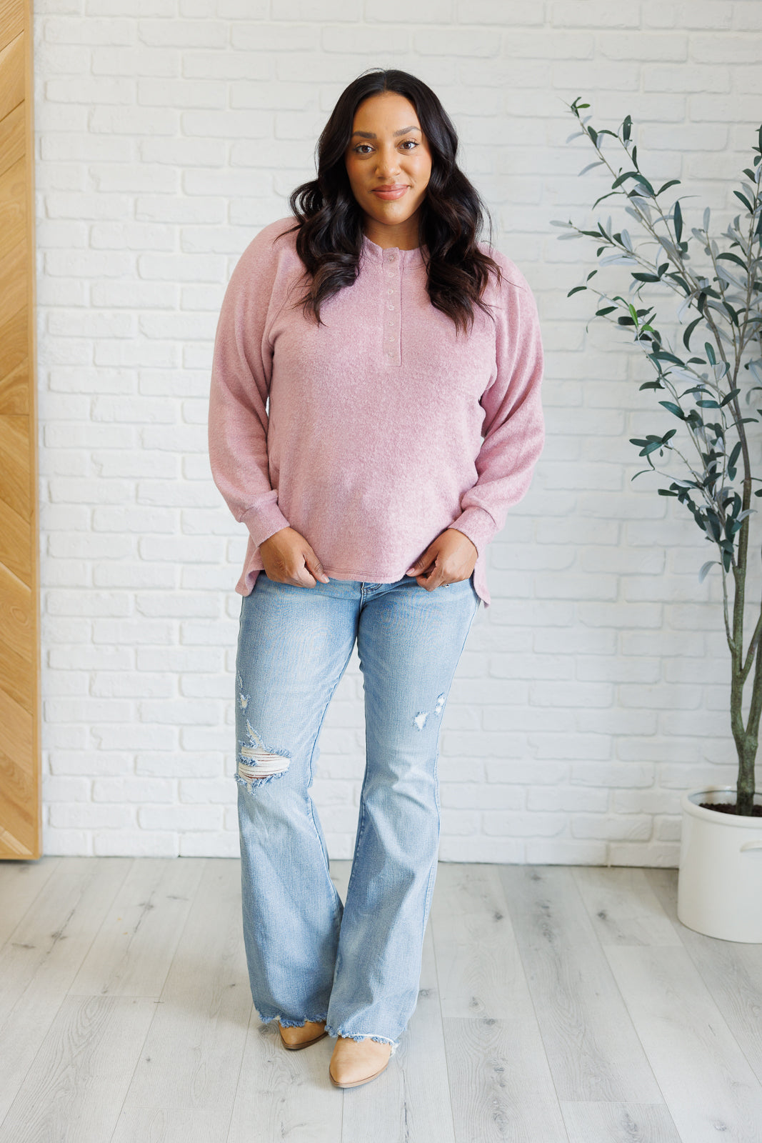 Light rose long-sleeve tee made from soft melange hacci knit fabric. Features a round neckline with half-snap buttons, raglan sleeves, and banded cuffs.