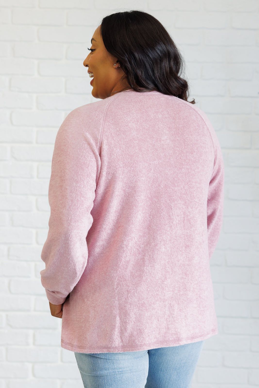 Light rose long-sleeve tee made from soft melange hacci knit fabric. Features a round neckline with half-snap buttons, raglan sleeves, and banded cuffs.