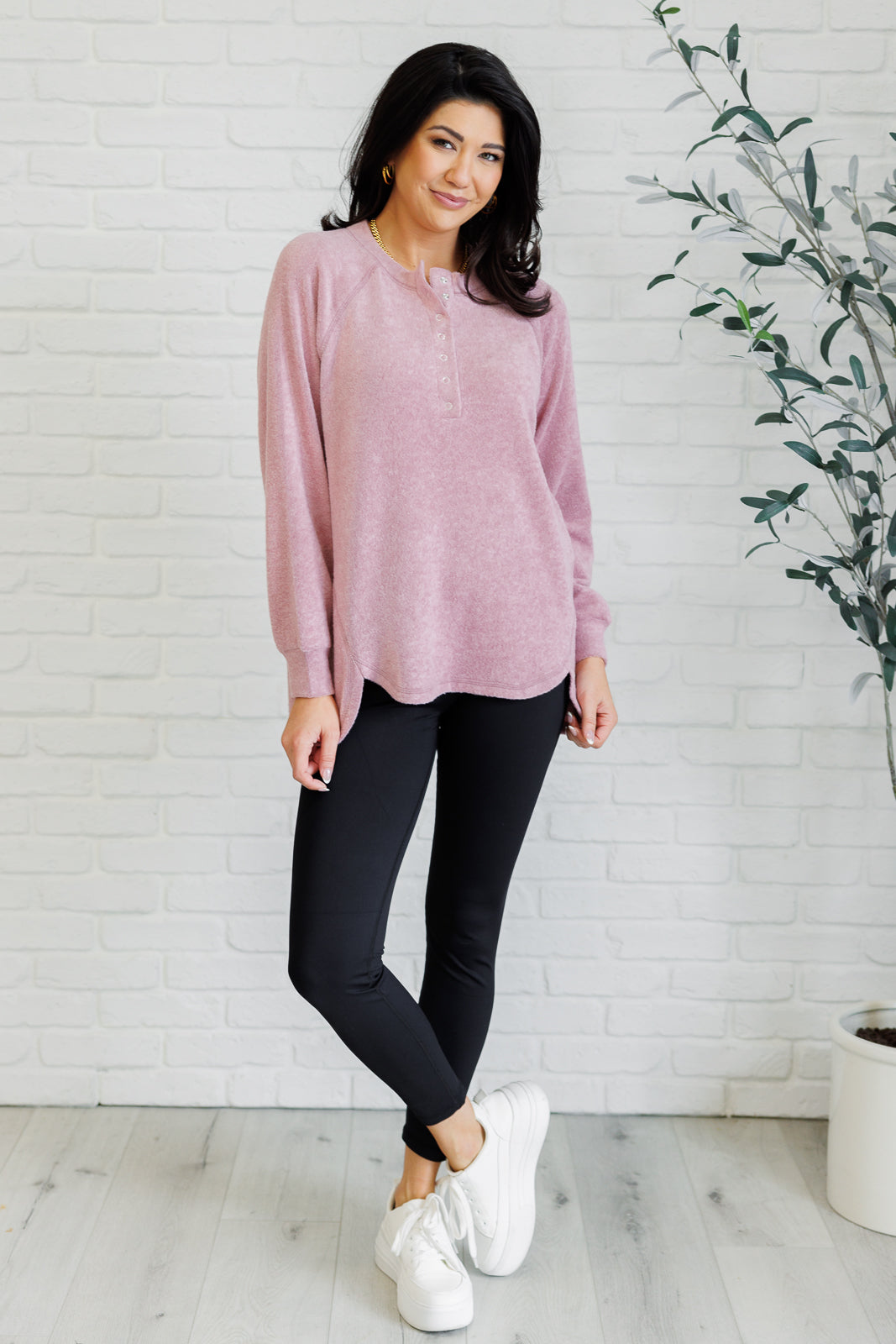 Light rose long-sleeve tee made from soft melange hacci knit fabric. Features a round neckline with half-snap buttons, raglan sleeves, and banded cuffs.