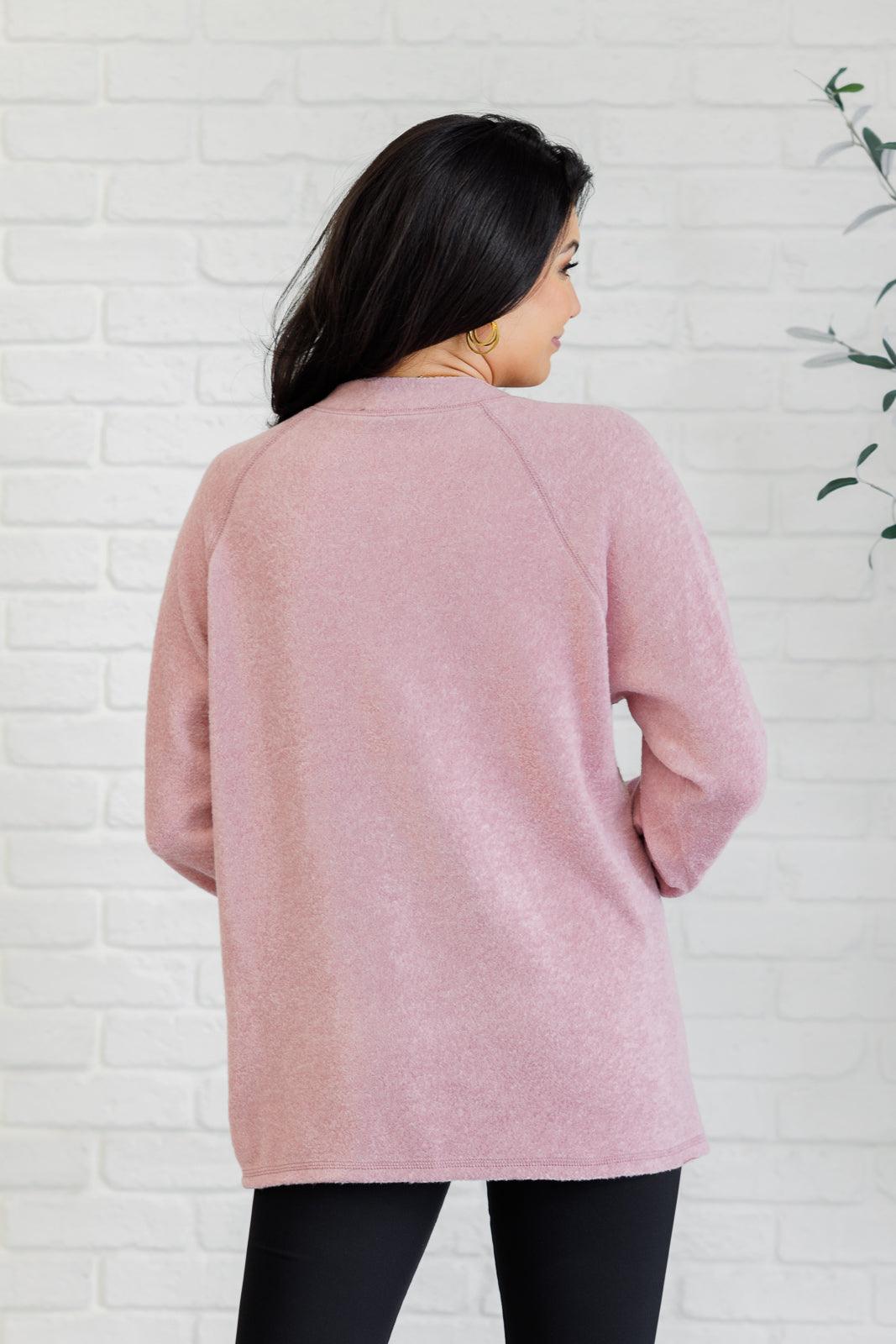 Light rose long-sleeve tee made from soft melange hacci knit fabric. Features a round neckline with half-snap buttons, raglan sleeves, and banded cuffs.