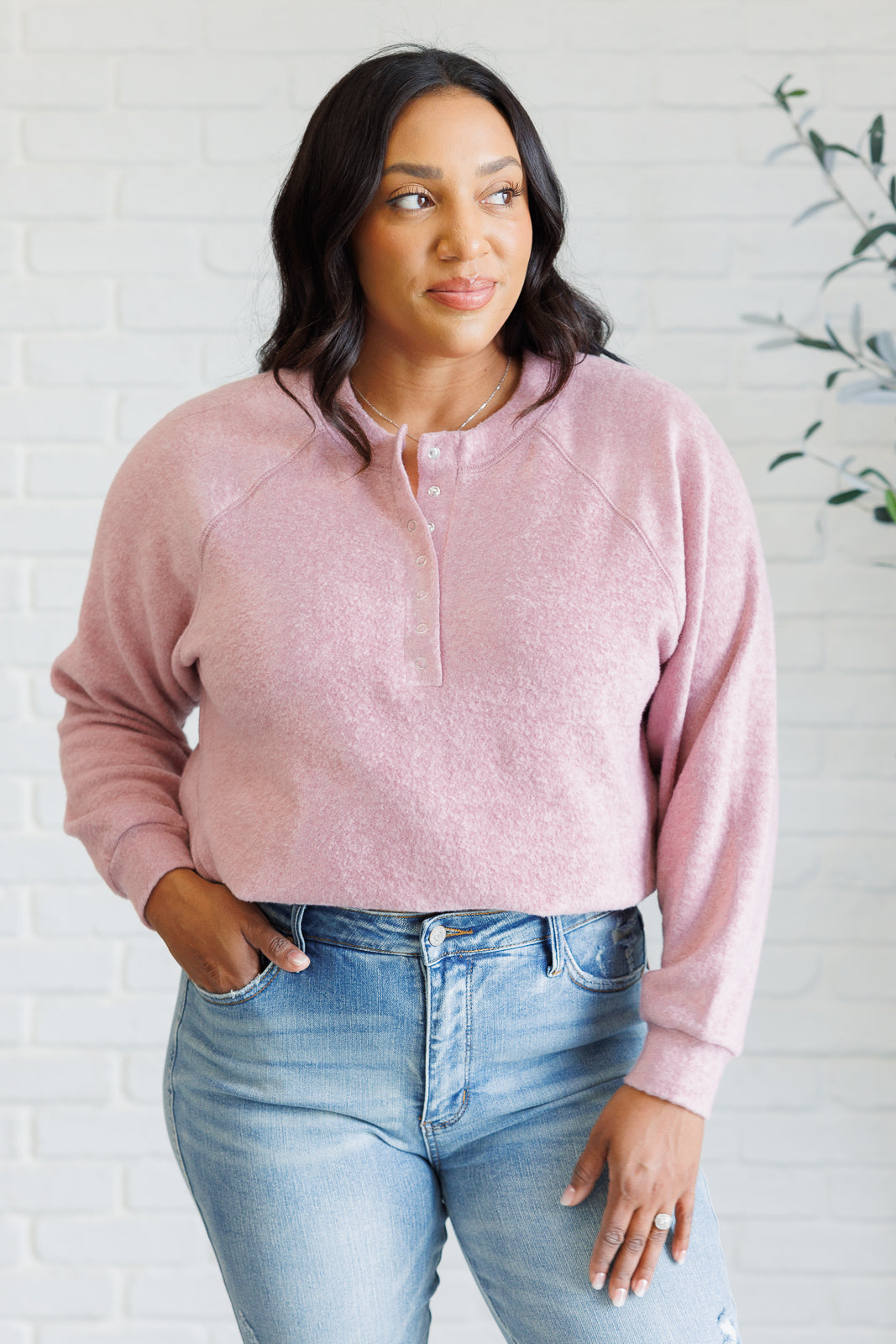 Light rose long-sleeve tee made from soft melange hacci knit fabric. Features a round neckline with half-snap buttons, raglan sleeves, and banded cuffs.