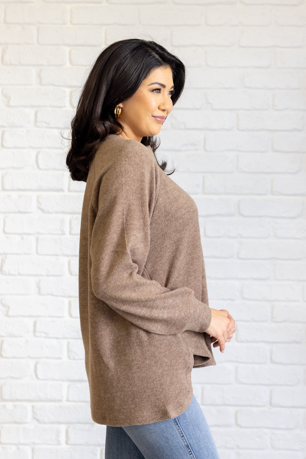 Mocha long-sleeve tee made from soft melange hacci knit fabric. Features a round neckline with half-snap buttons, raglan sleeves, and banded cuffs.