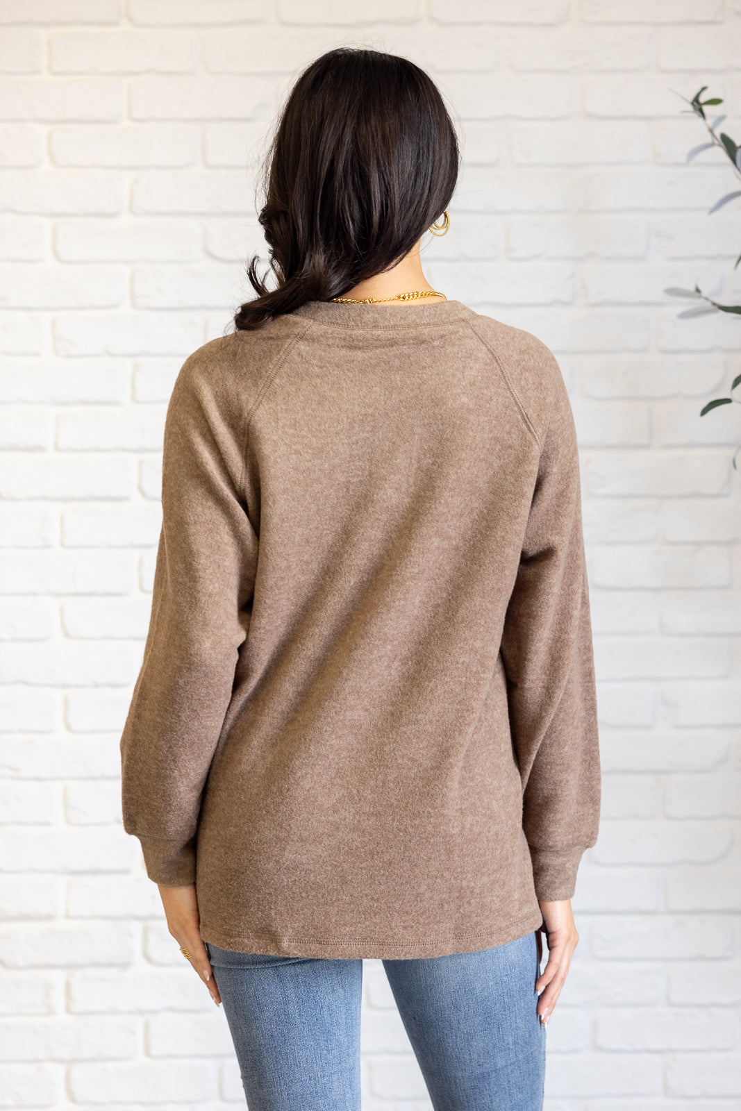 Mocha long-sleeve tee made from soft melange hacci knit fabric. Features a round neckline with half-snap buttons, raglan sleeves, and banded cuffs.