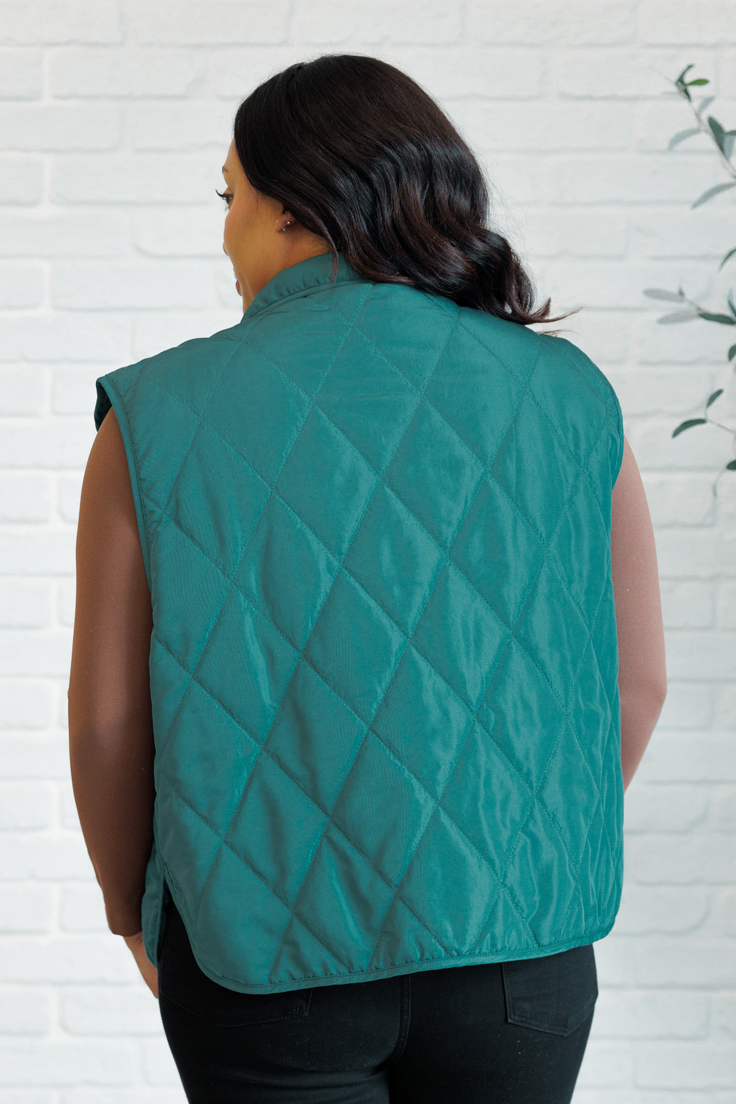 Hunter green puffer vest made from quilted windbreaker material. Features a high neckline, snap button closures, and functional side pockets. Fully lined with a round hemline.