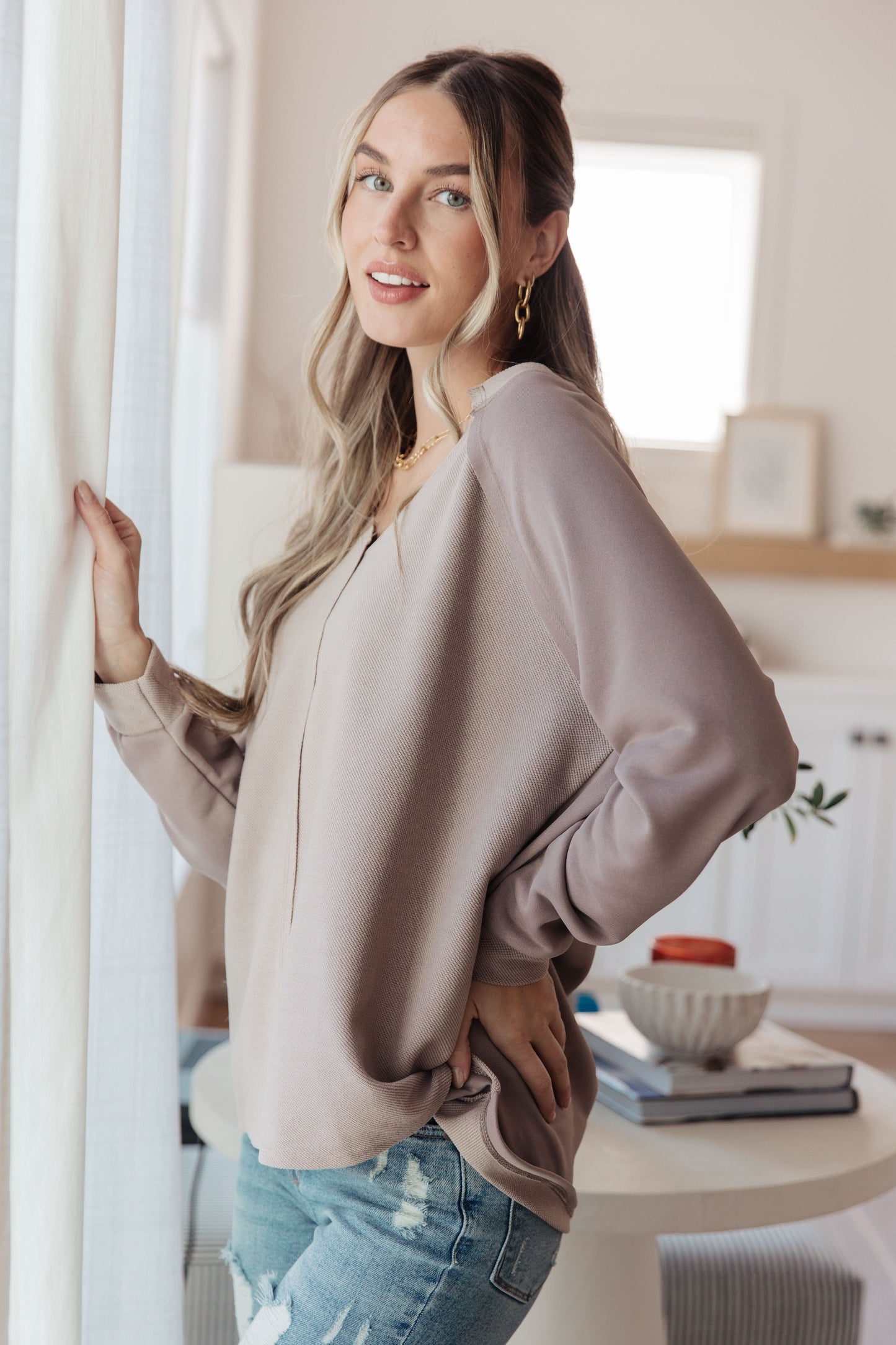 Side profile of Dominique V-Neck Top, beige textured knit with raw edge finish