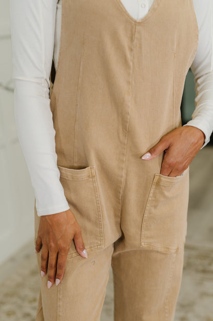 Close-up: Close-up of Litzy Jumpsuit in Brush with woven cotton fabric, bronze strap hardware, and functional patch pocket detail.