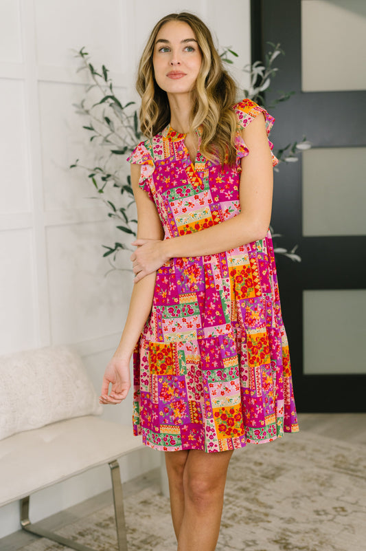 Model wearing Lizzy Flutter Sleeve Dress in Pink Multi patchwork floral with tiered skirt and pockets.
