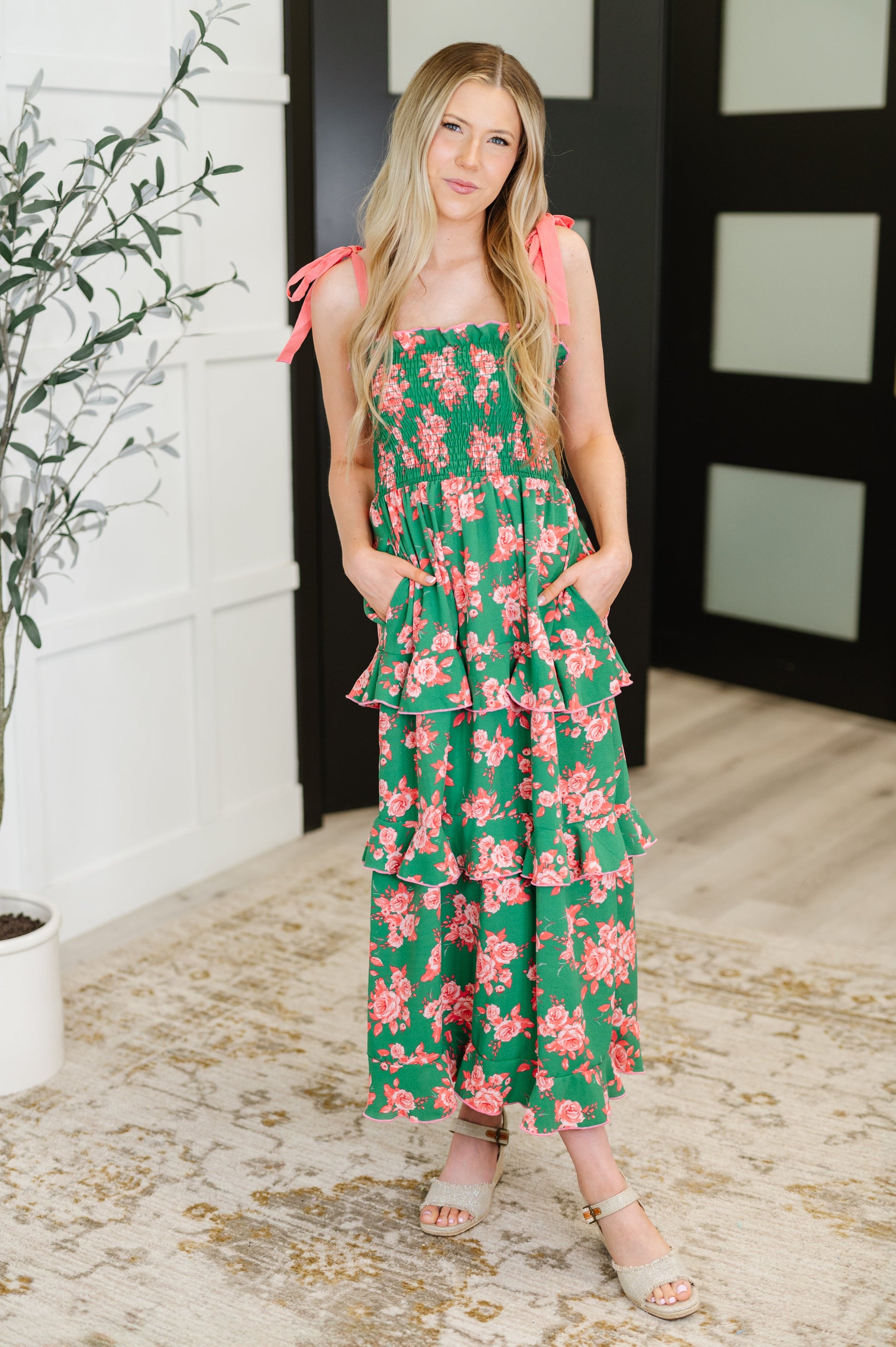 Model wearing Lorna Tiered Dress in Green and Coral floral with smocked bodice and tiered skirt.