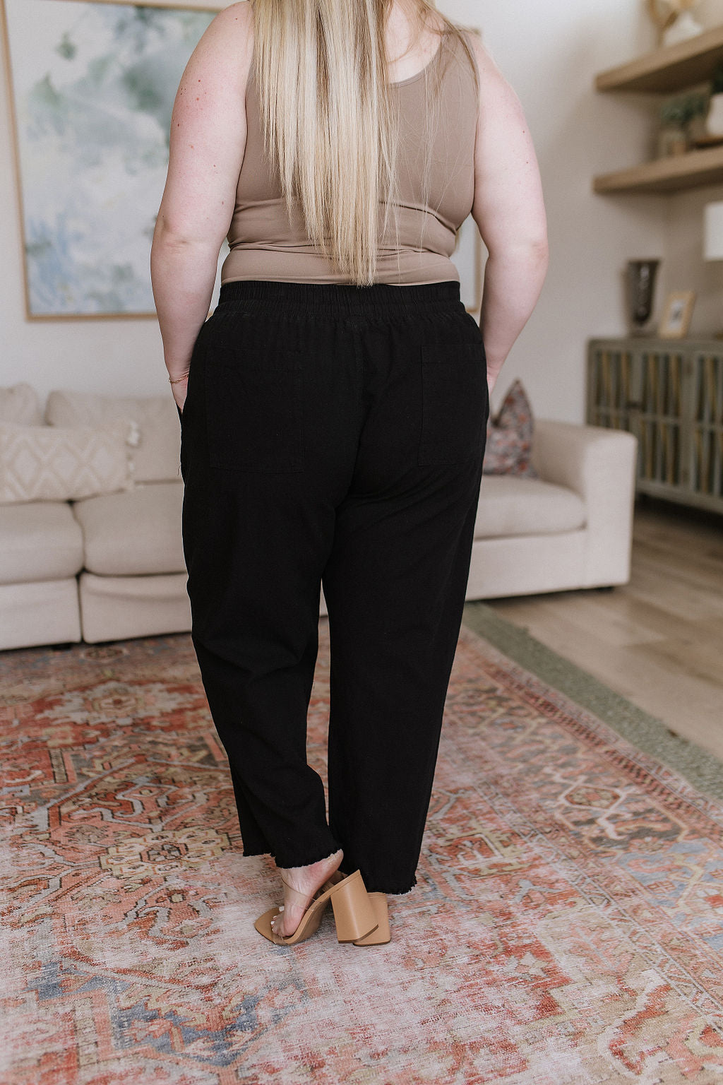 Black high-waisted pants with relaxed fit, raw hem, elastic waistband, and functional drawstring.