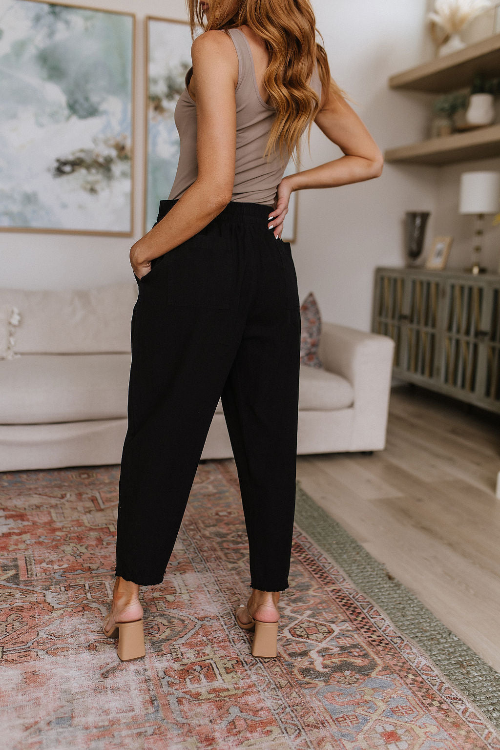 Black high-waisted pants with relaxed fit, raw hem, elastic waistband, and functional drawstring.