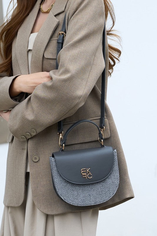 Woman holding gray Heloise herringbone crossbody bag over shoulder.