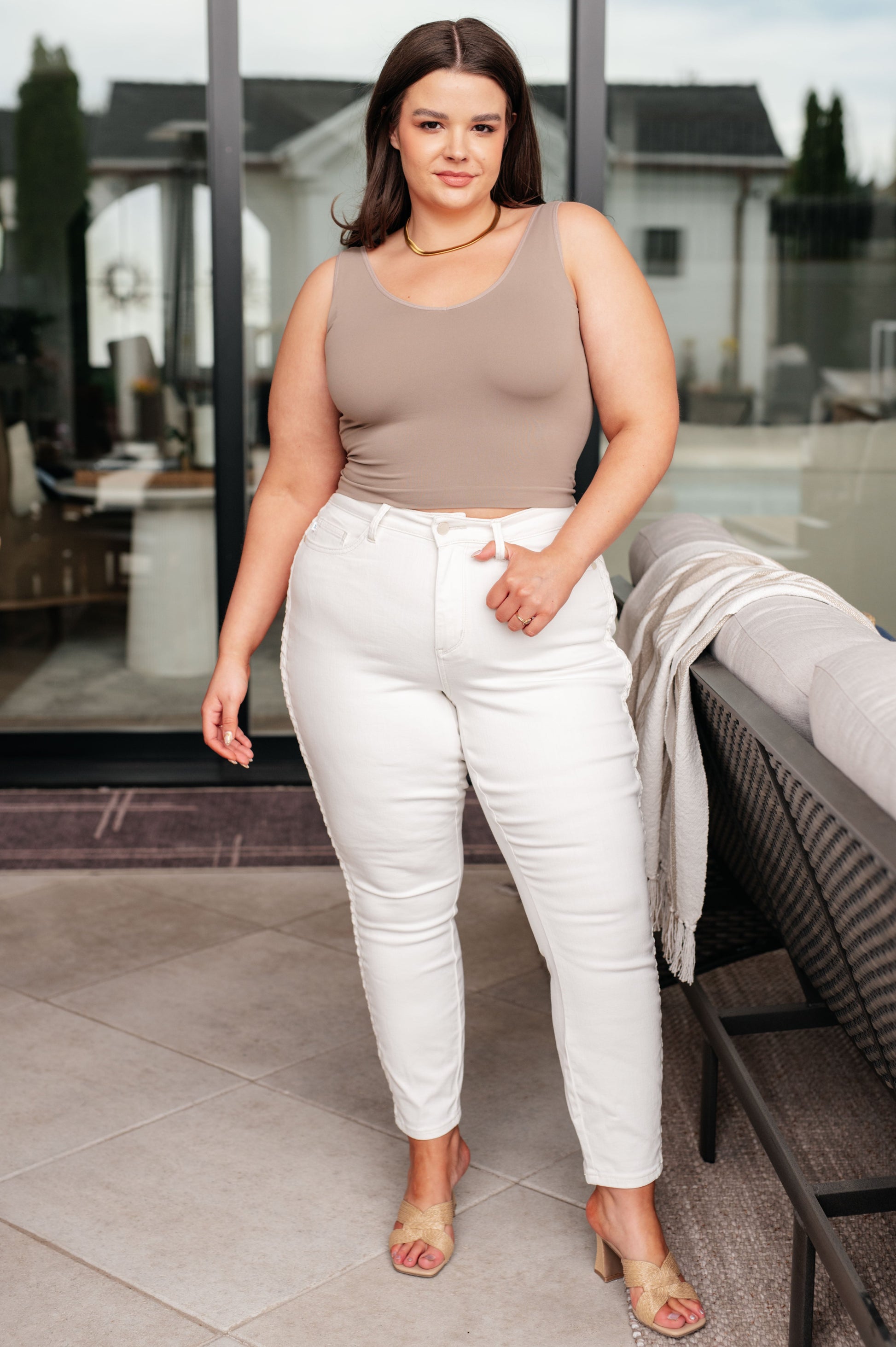 Plus size model wearing Maddie Mid Rise Braided Side Seam Jeans in white Judy Blue denim with taupe tank and heels.