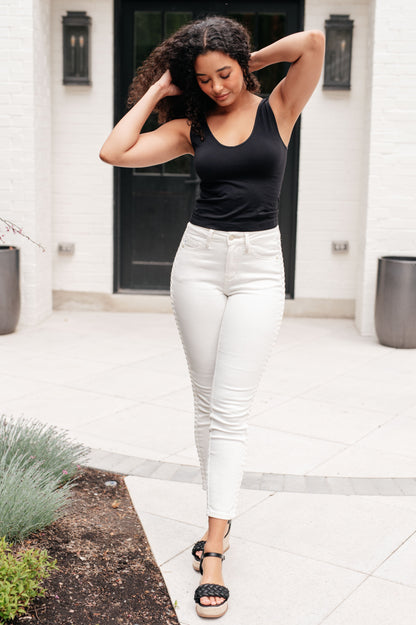 Full body view of Maddie Mid Rise Braided Side Seam Jeans in white Judy Blue denim styled with black tank and sandals.