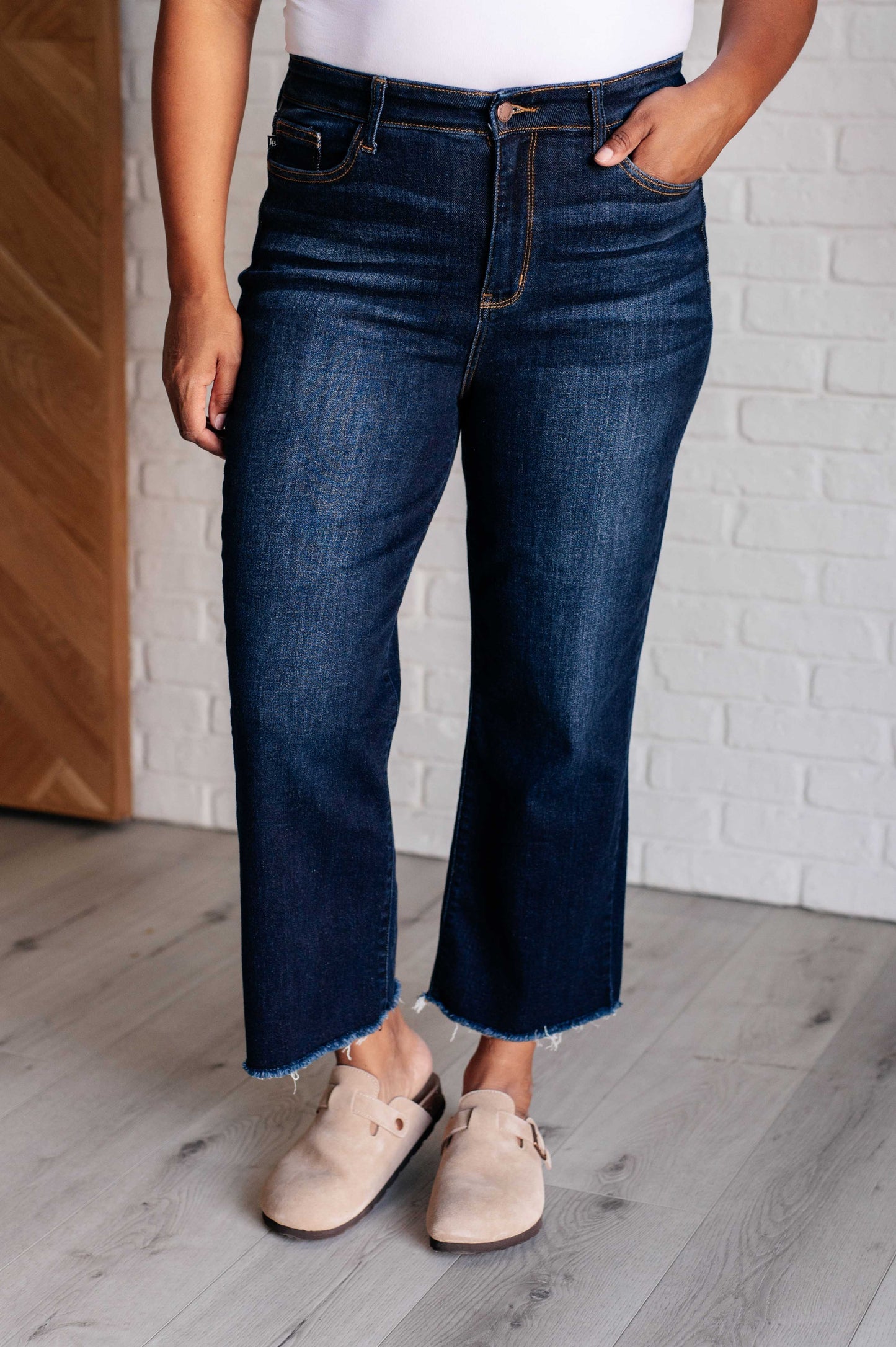 Judy Blue dark wash high-rise cropped wide leg jeans with a raw hem, tummy control technology, and 4-way stretch for comfort. Features a zip fly and control top.