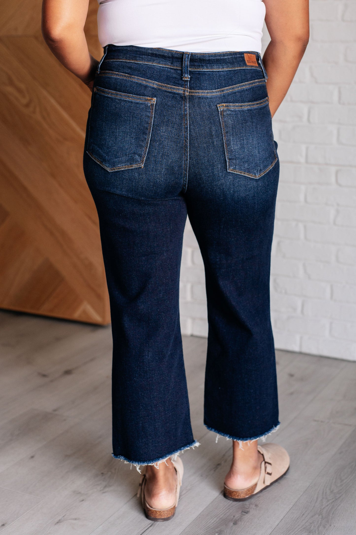 Judy Blue dark wash high-rise cropped wide leg jeans with a raw hem, tummy control technology, and 4-way stretch for comfort. Features a zip fly and control top.