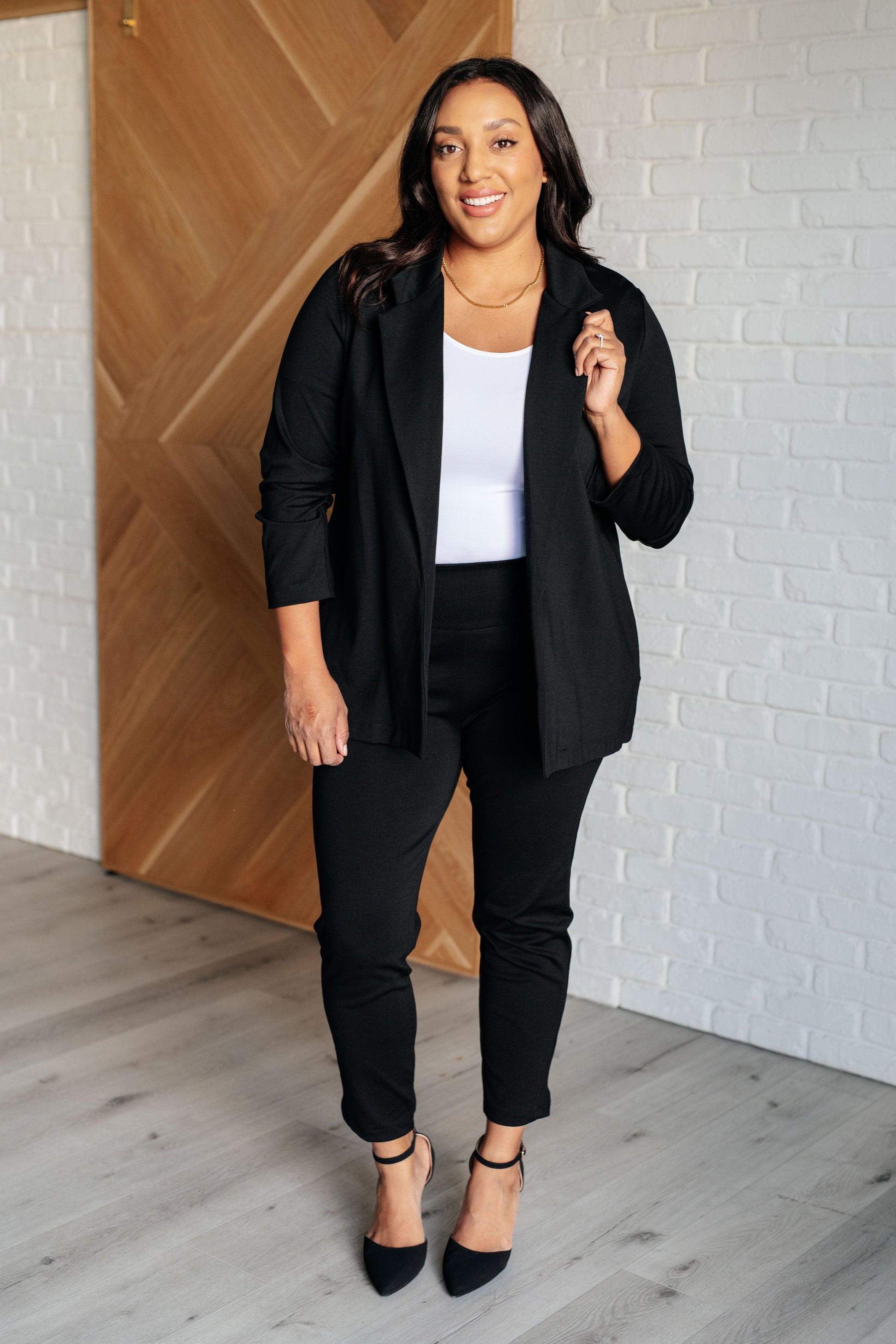 Black blazer with ruched 3/4 sleeves, open front, and notched lapel. Made from ponte knit with side pockets and a slim fit.