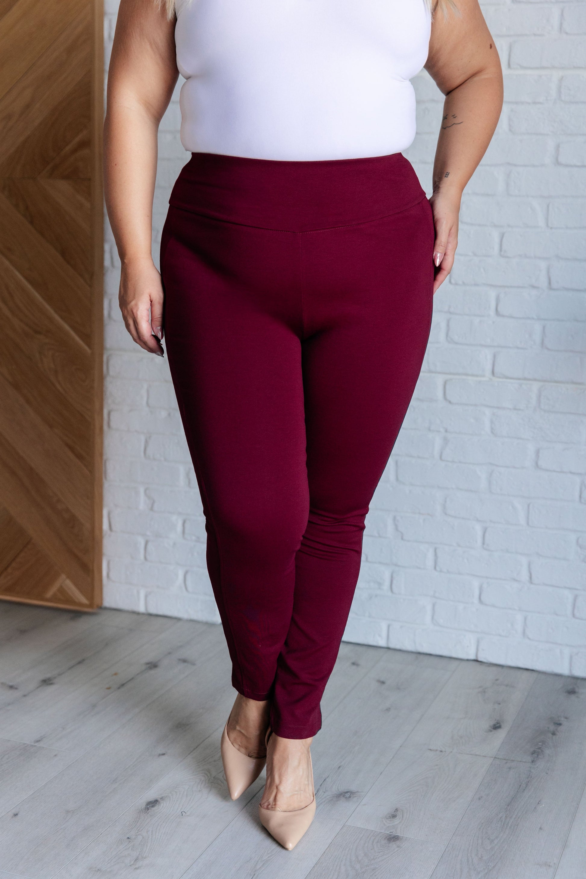 Skinny Pants in wine with high-rise, slim fit, and ponte knit fabric. Features tuxedo stripes, faux welt pockets, and an elastic waistband.