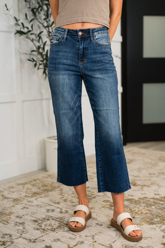 Woman wearing Maisie High Waist Crop Wide jeans in dark wash with wide leg and raw hem, front view.