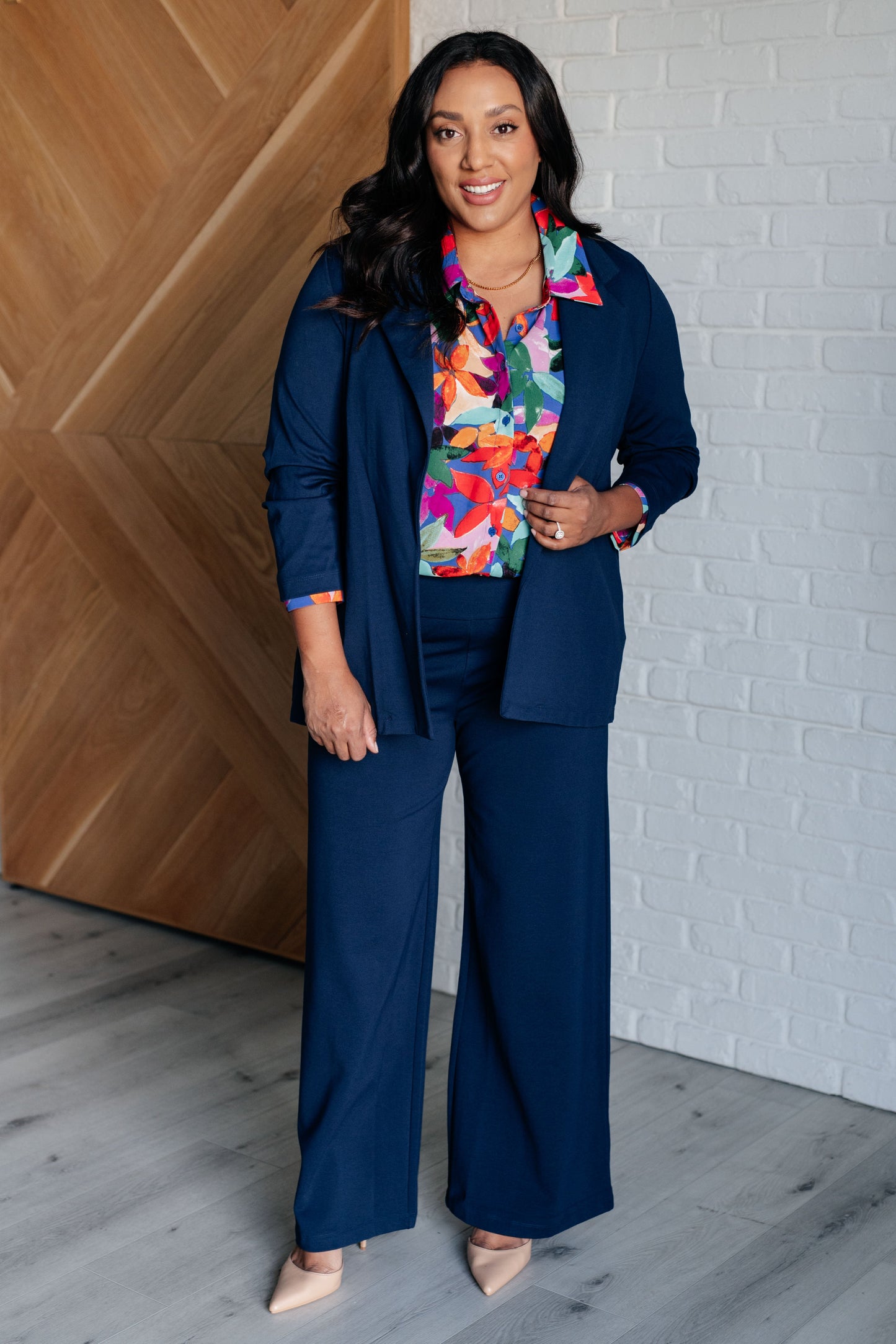 Floral multicolored button-up blouse with a collared neckline, long balloon sleeves, and a scooped hem. Features front button closures and banded cuffs.