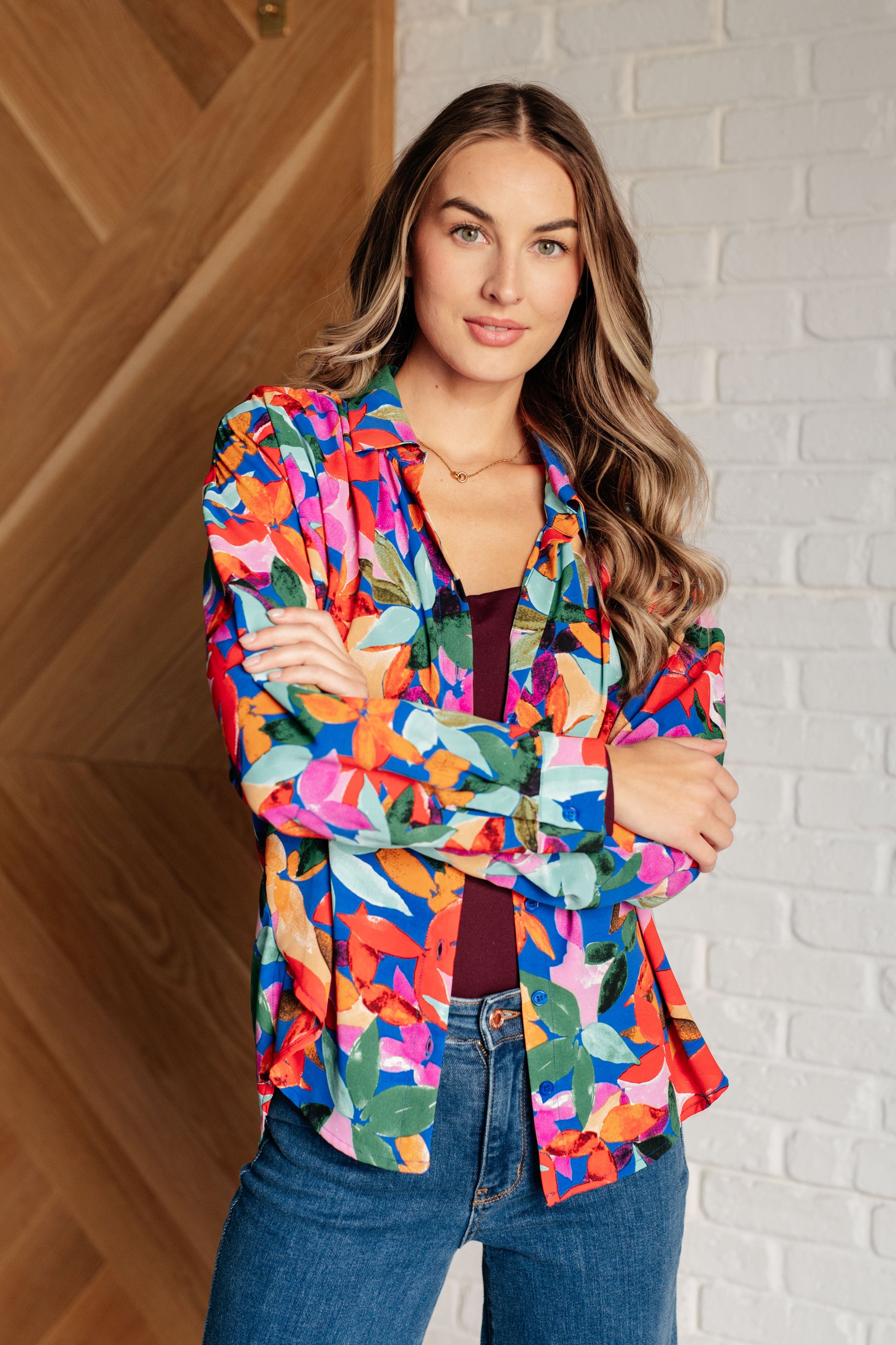 Floral multicolored button-up blouse with a collared neckline, long balloon sleeves, and a scooped hem. Features front button closures and banded cuffs.