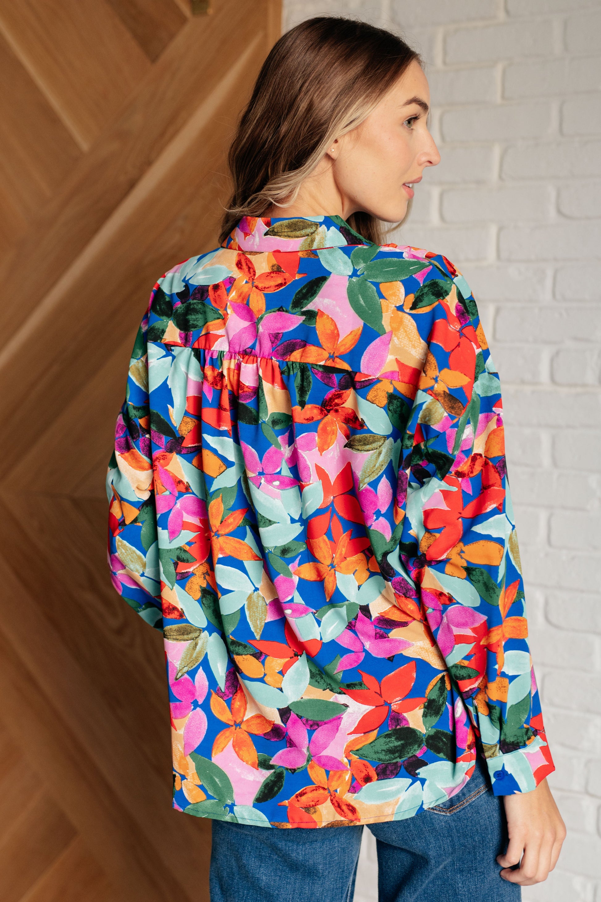 Floral multicolored button-up blouse with a collared neckline, long balloon sleeves, and a scooped hem. Features front button closures and banded cuffs.