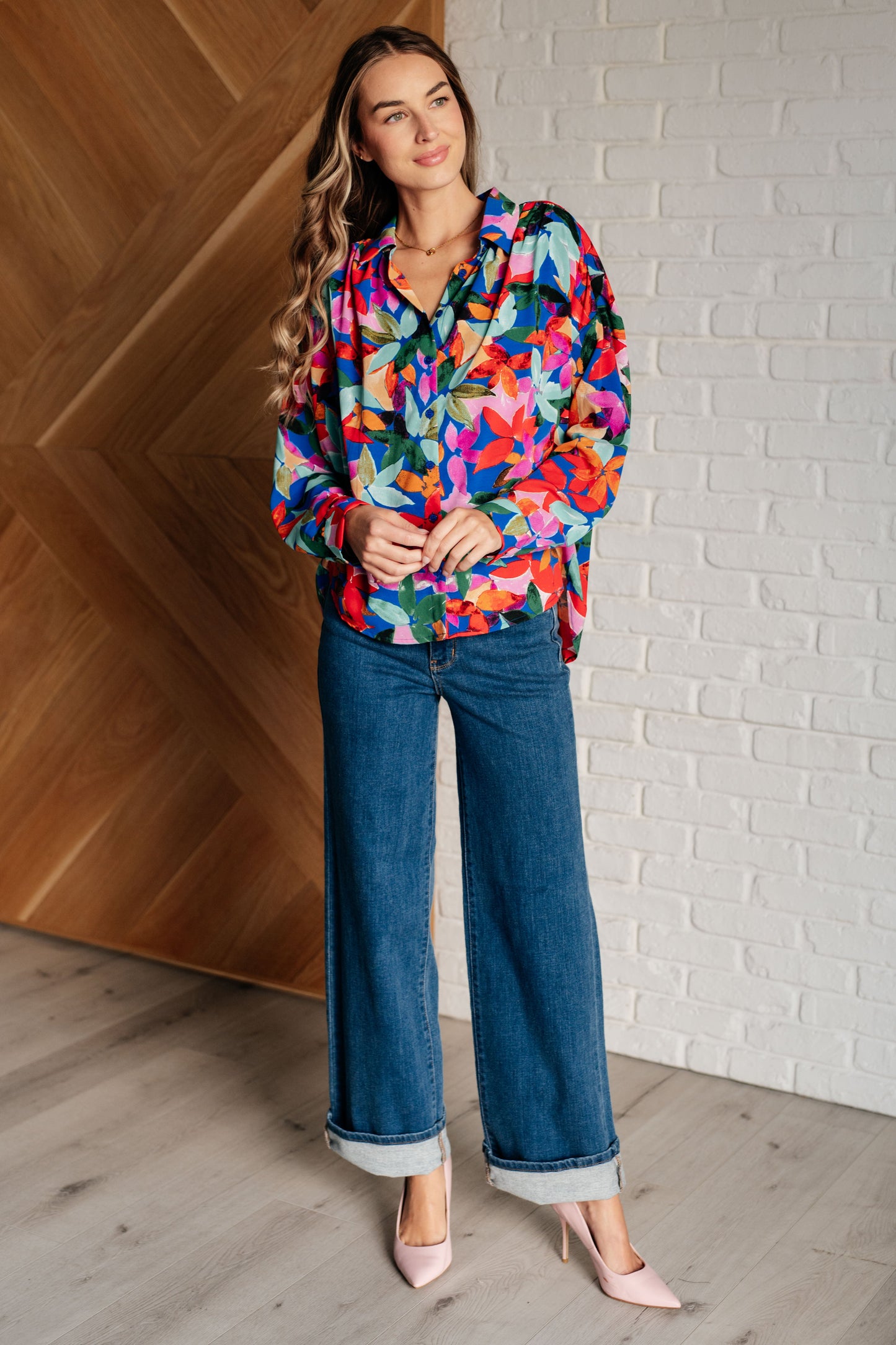 Floral multicolored button-up blouse with a collared neckline, long balloon sleeves, and a scooped hem. Features front button closures and banded cuffs.