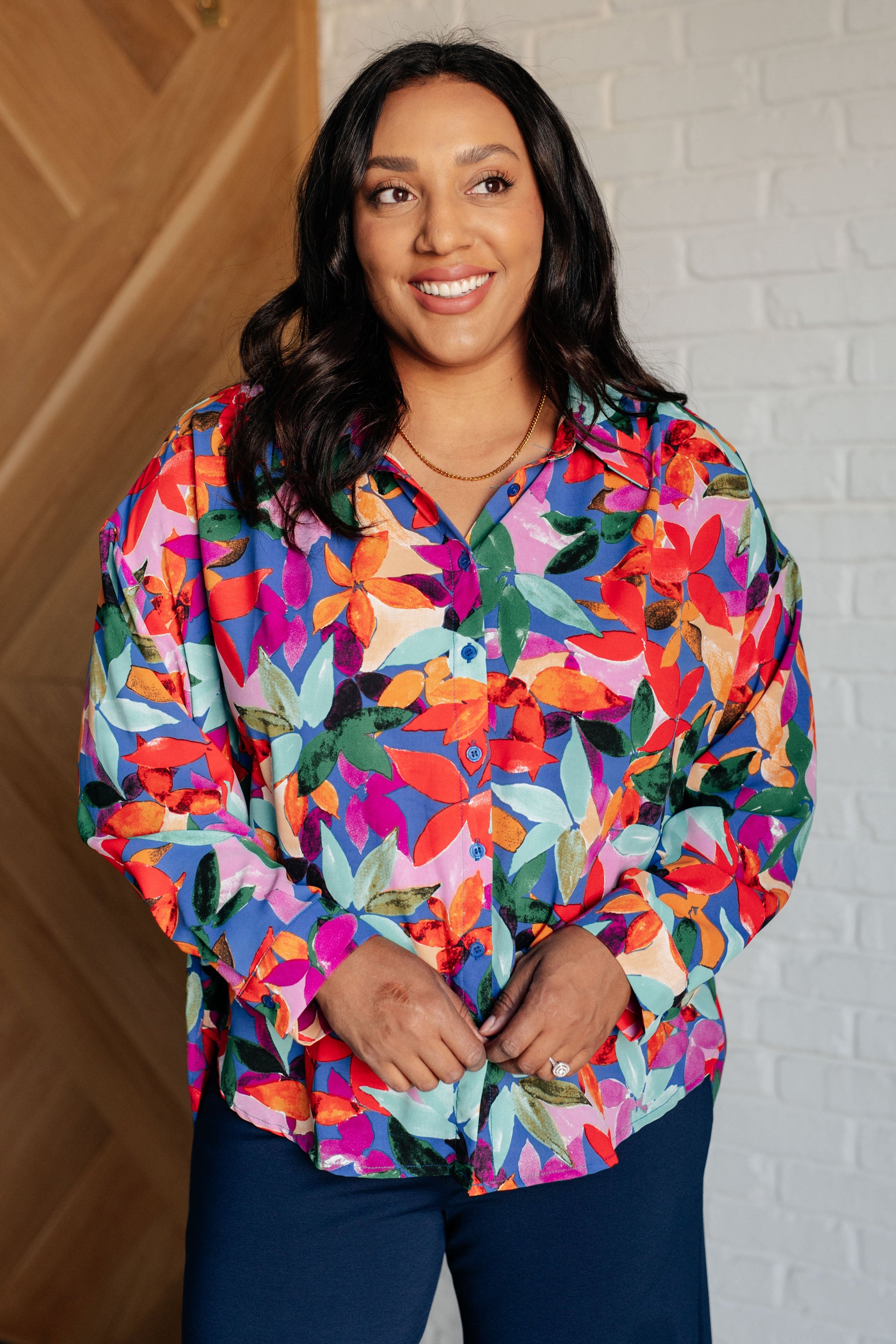 Floral multicolored button-up blouse with a collared neckline, long balloon sleeves, and a scooped hem. Features front button closures and banded cuffs.