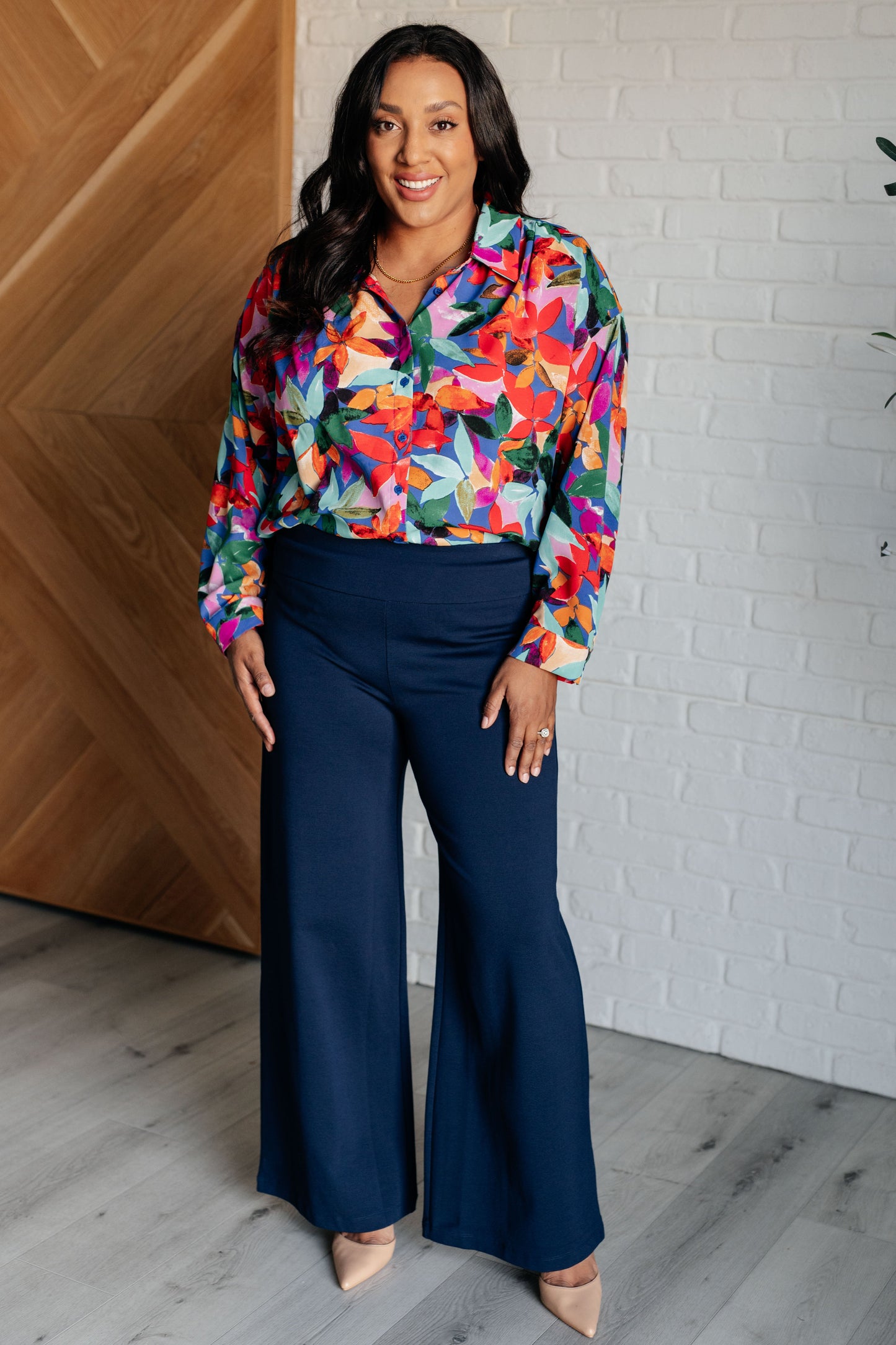 Floral multicolored button-up blouse with a collared neckline, long balloon sleeves, and a scooped hem. Features front button closures and banded cuffs.