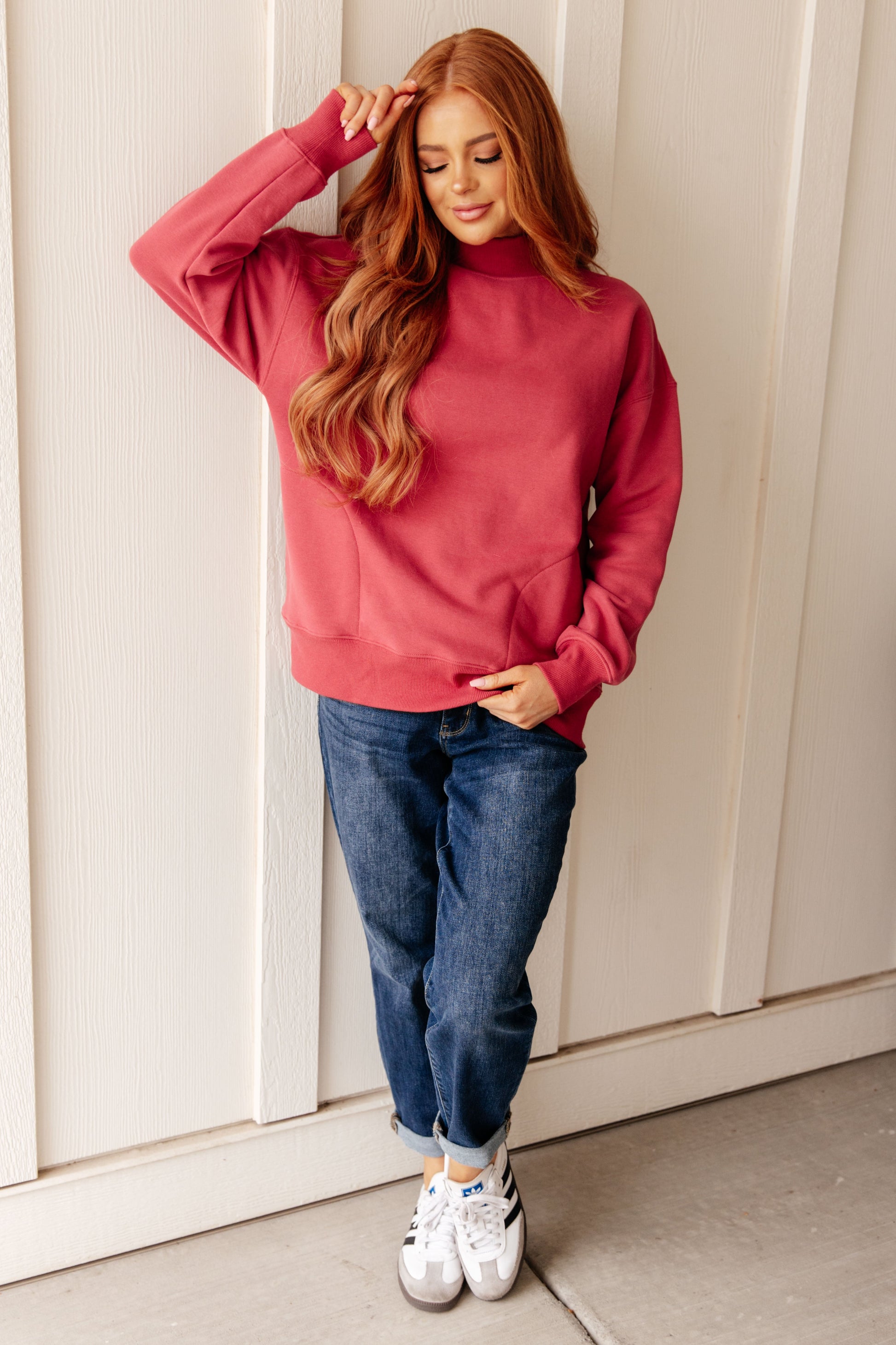 Soft cranberry-colored sweatshirt fleece pullover with a ribbed mock neckline, long sleeves, dropped shoulders, side pockets, and a relaxed fit.