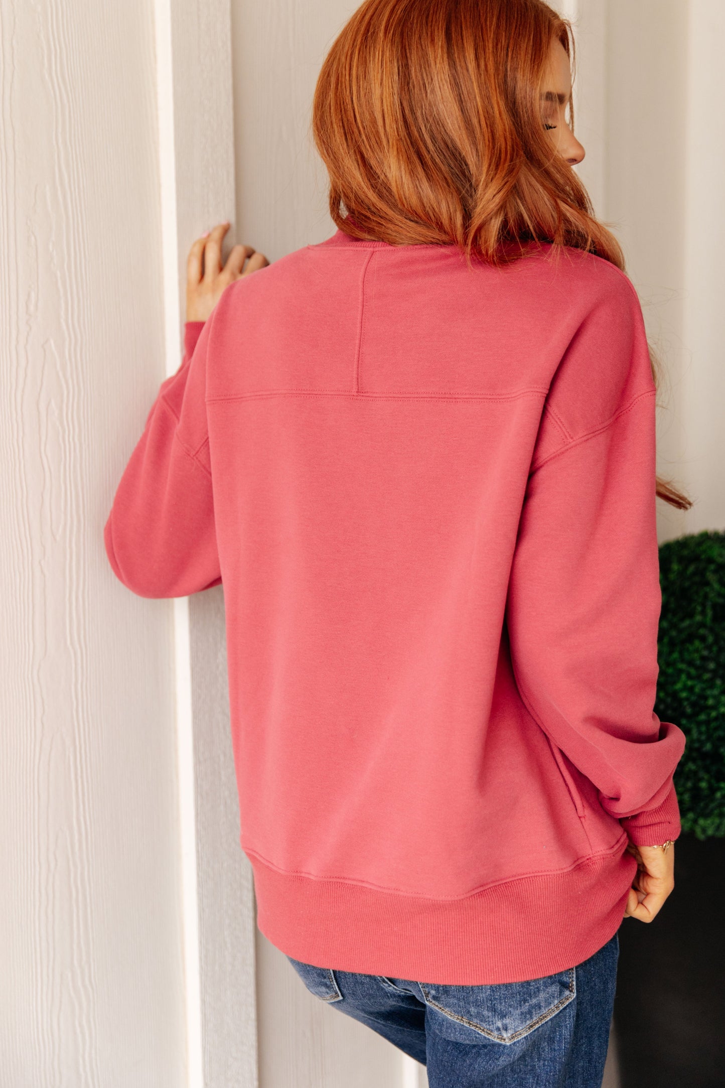 Soft cranberry-colored sweatshirt fleece pullover with a ribbed mock neckline, long sleeves, dropped shoulders, side pockets, and a relaxed fit.