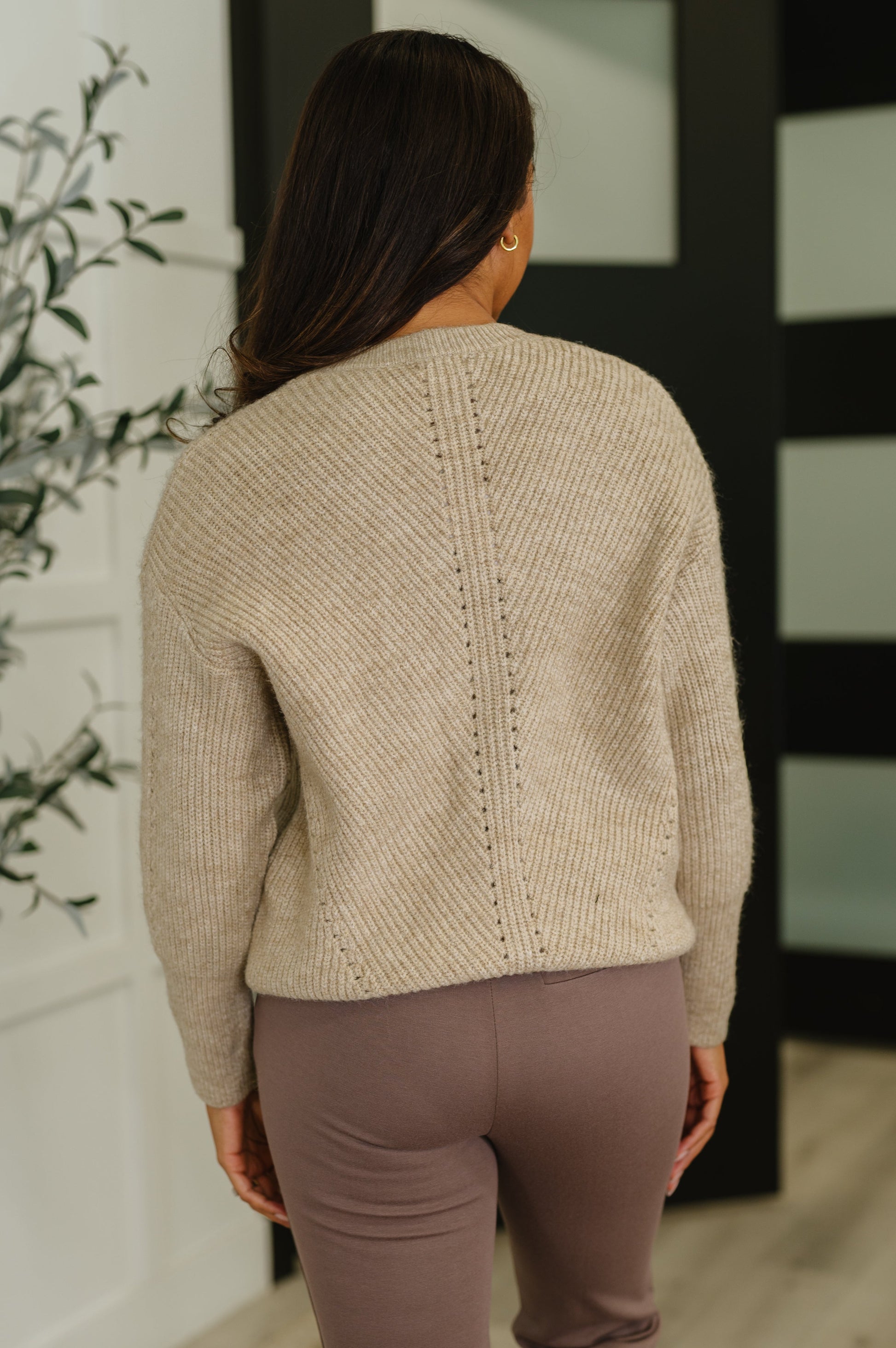 Back view of beige textured knit sweatshirt with banded ribbed hemline and relaxed fit.
