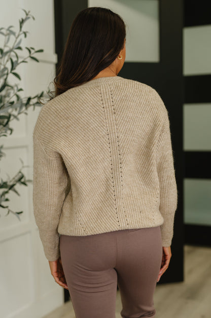 Back view of beige textured knit sweatshirt with banded ribbed hemline and relaxed fit.