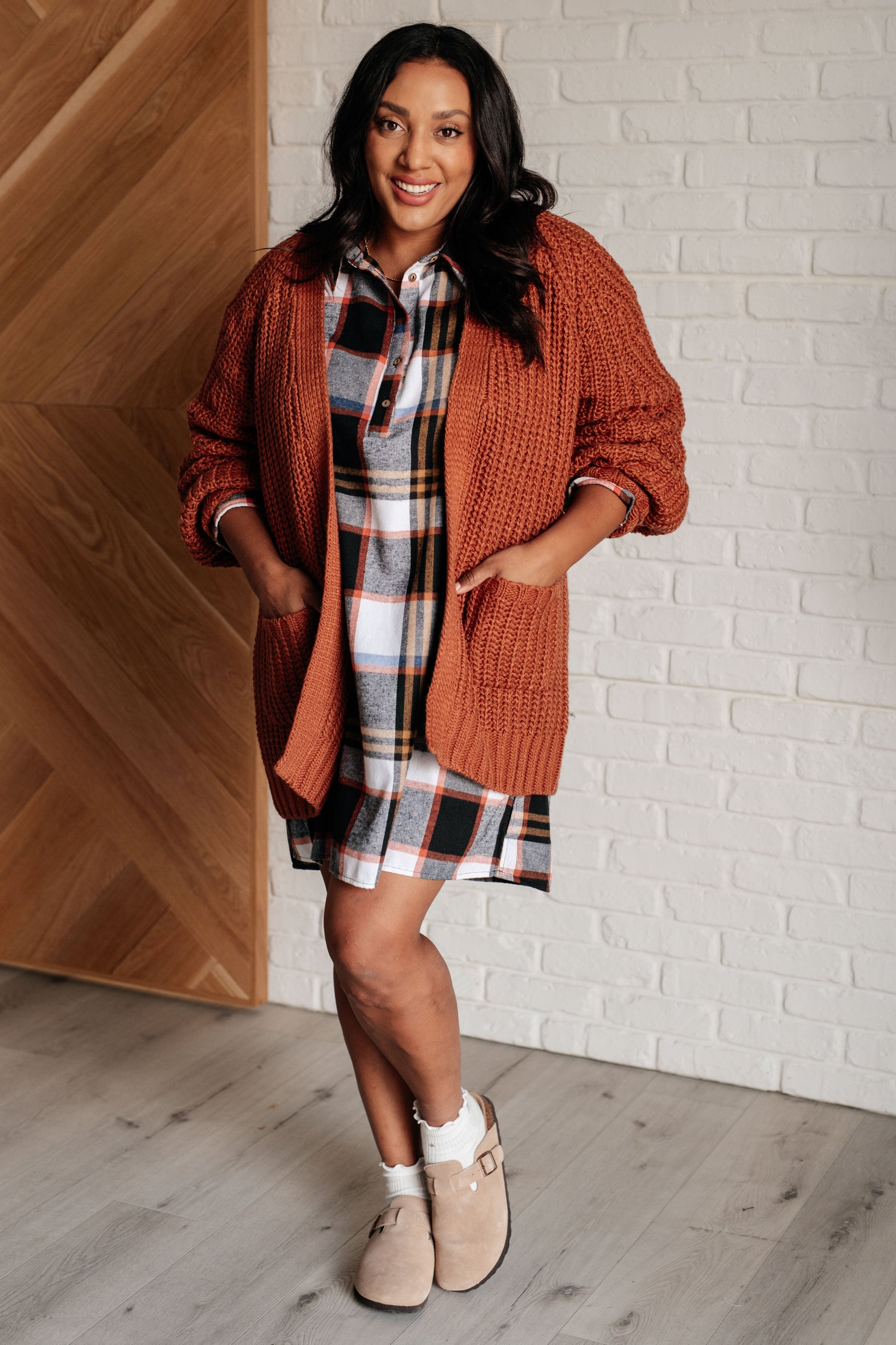 Black plaid flannel shirt dress with a collared neckline, button front closure, and long sleeves with roll button tabs. and side slits.