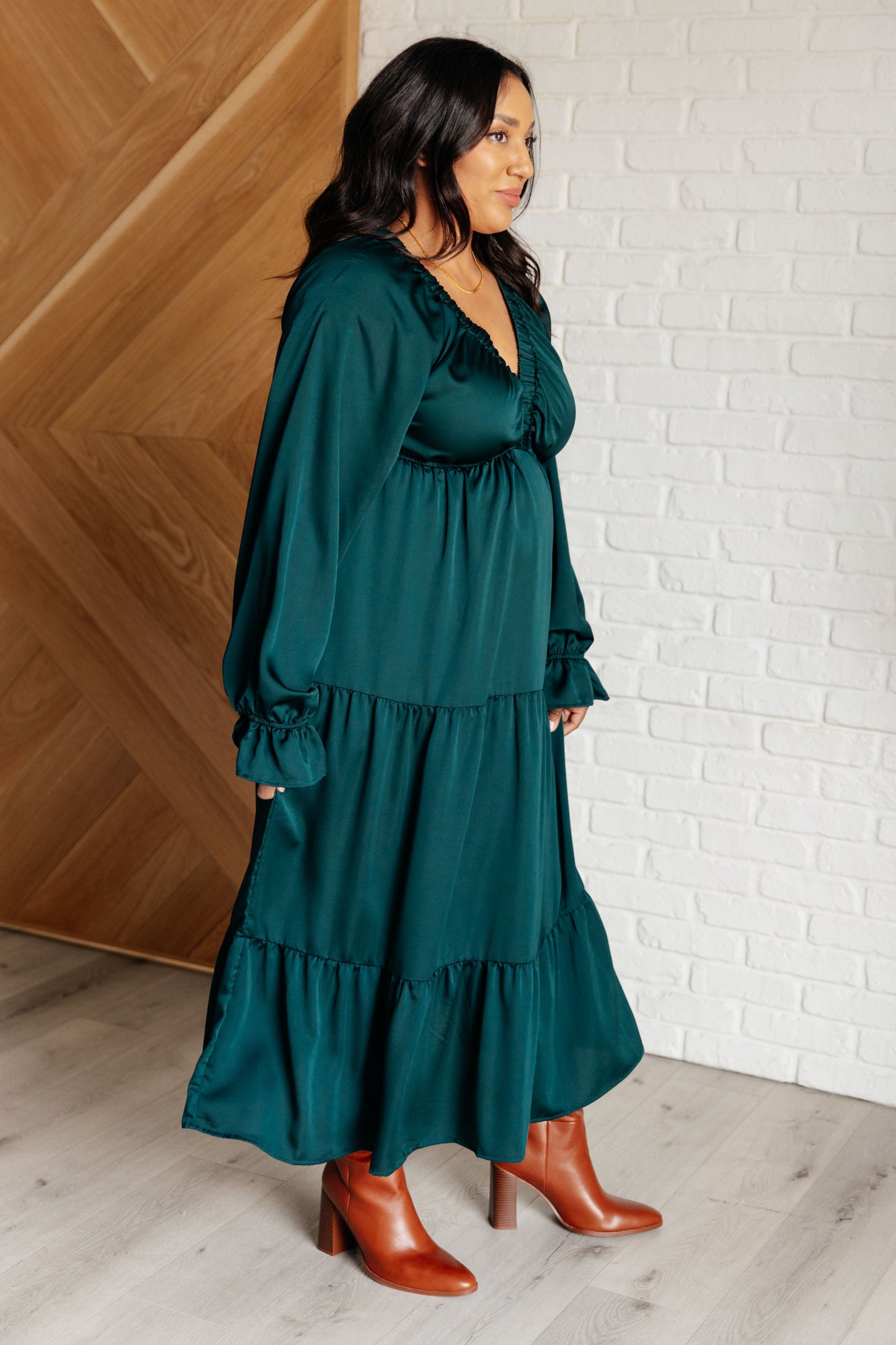 Hunter green poly satin tiered dress with V-neck, long balloon sleeves, and elastic at the neck, shoulders, and sleeve cuffs. Elastic empire waist and functional side pockets.