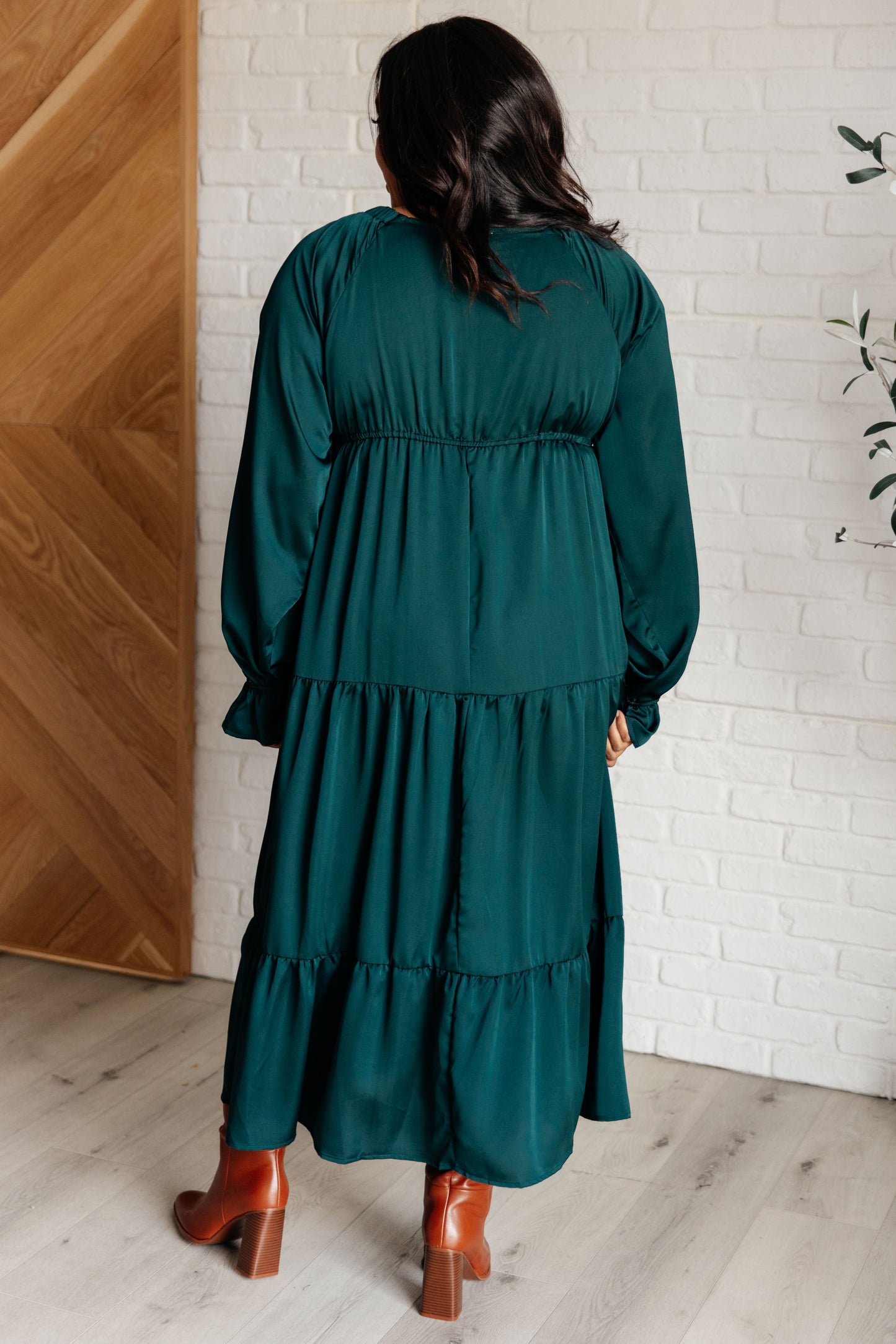 Hunter green poly satin tiered dress with V-neck, long balloon sleeves, and elastic at the neck, shoulders, and sleeve cuffs. Elastic empire waist and functional side pockets.