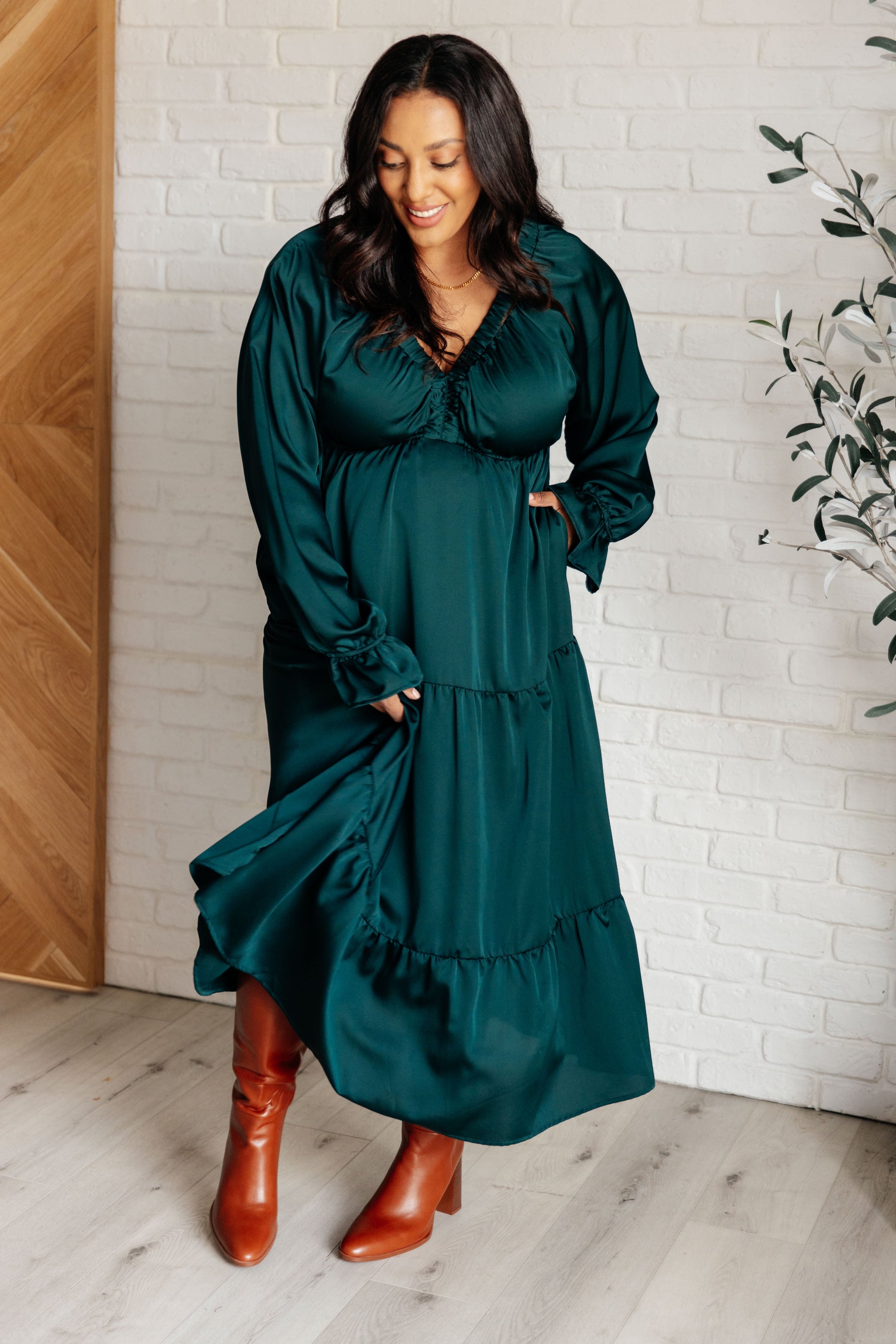 Hunter green poly satin tiered dress with V-neck, long balloon sleeves, and elastic at the neck, shoulders, and sleeve cuffs. Elastic empire waist and functional side pockets.