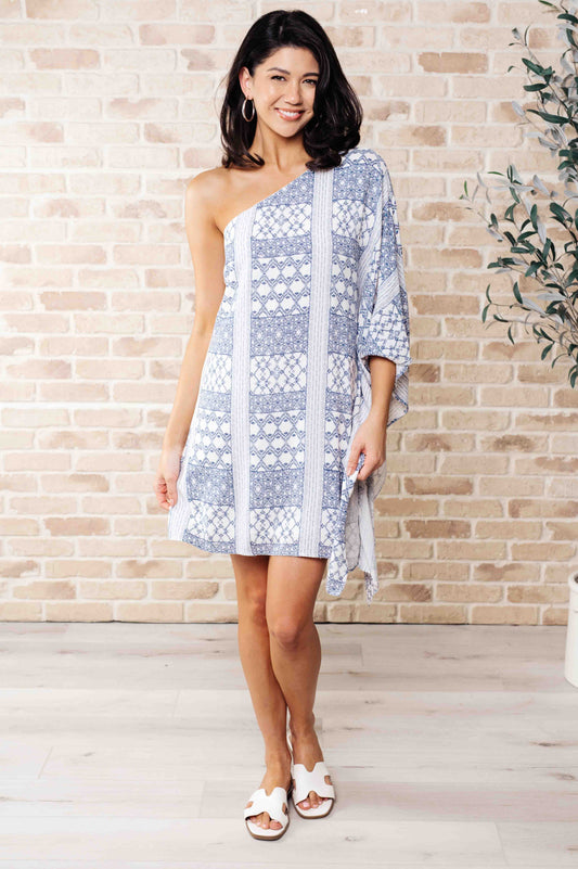 Front view of model wearing Marjorie One Shoulder Blue Dress with contrasting print, styled with sandals for a chic night-out look.