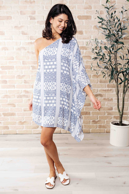 Full body view of model in Marjorie One Shoulder Blue Dress with contrasting print, draped neckline, and elegant shift silhouette.