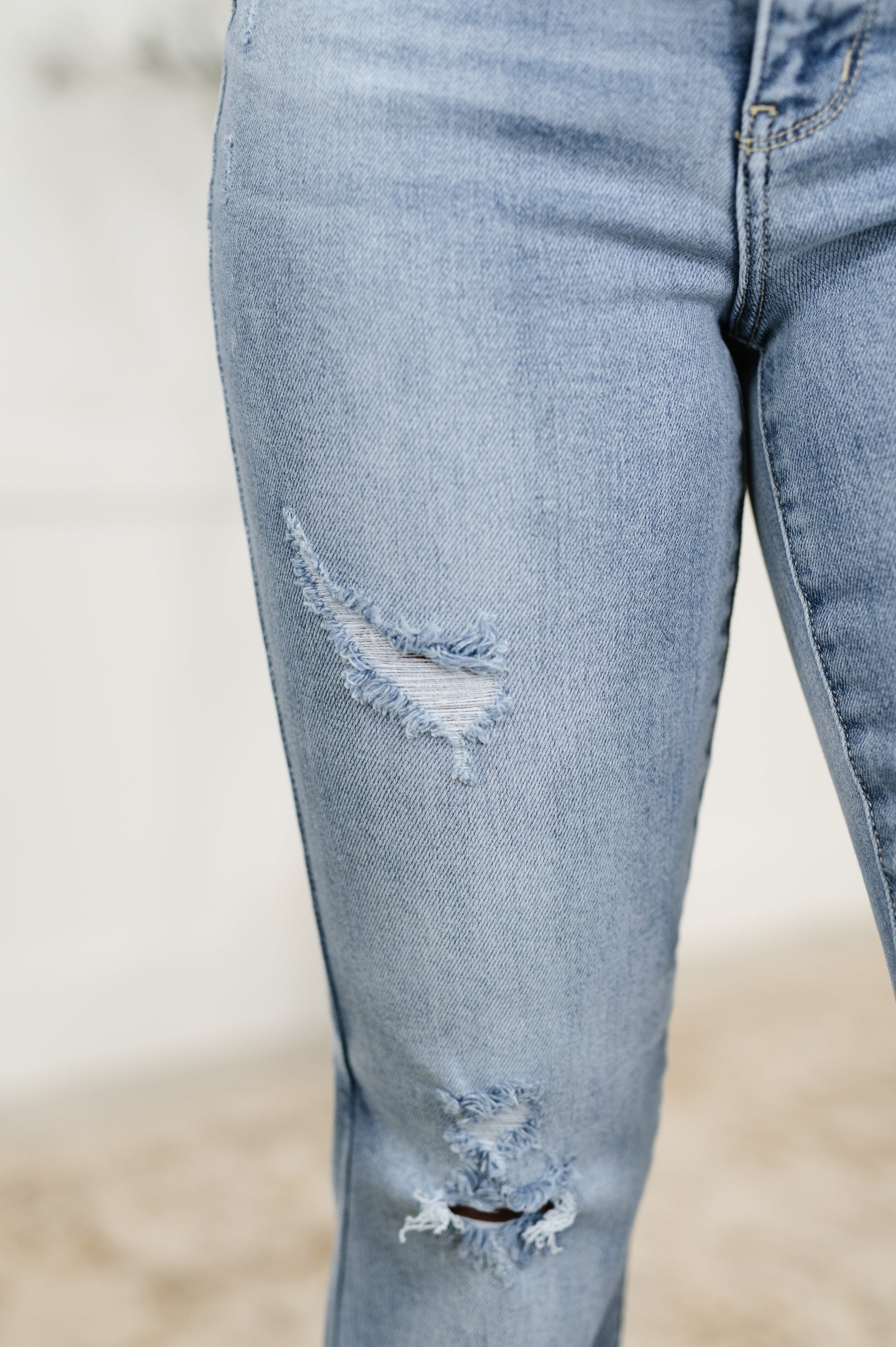 Close-up of Marlena High Rise Flare Jeans highlighting slight distressing and raw hemline in light wash denim.