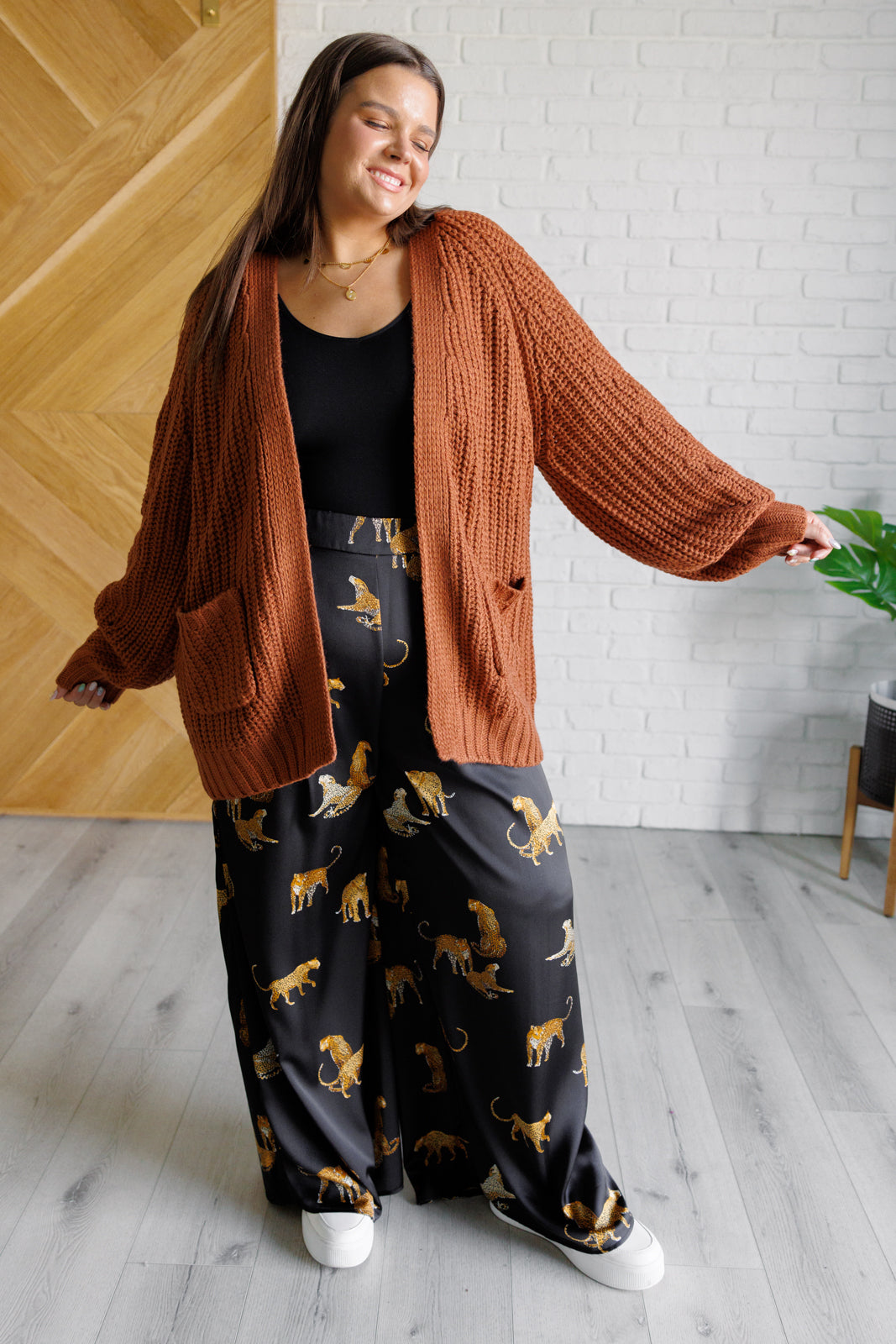 Women's long-line cardigan in chestnut sweater knit fabric with an open front, long sleeves, functional patch pockets, and exaggerated ribbed sleeve cuffs and hemline.