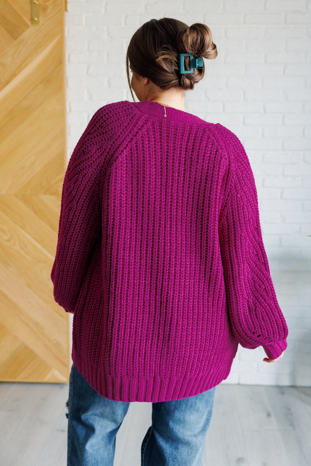 Women's long-line cardigan in the color berry sweater knit fabric with an open front, long sleeves, functional patch pockets, and exaggerated ribbed sleeve cuffs and hemline.