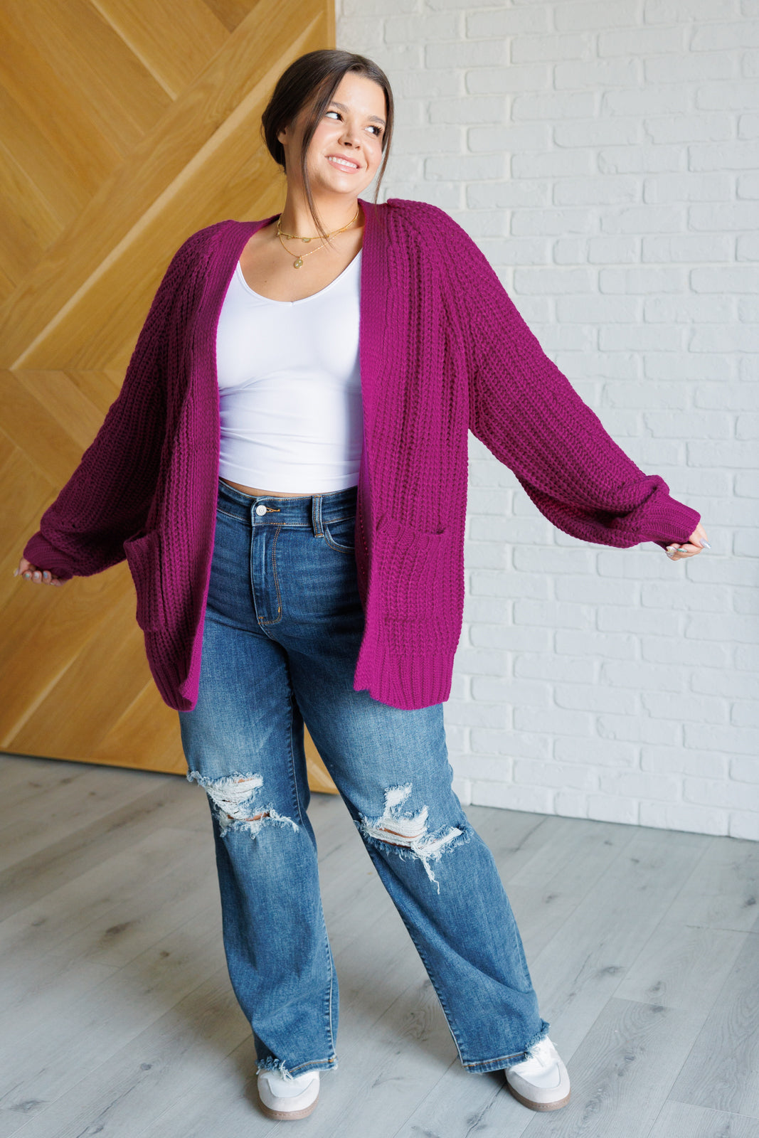 Women's long-line cardigan in the color berry sweater knit fabric with an open front, long sleeves, functional patch pockets, and exaggerated ribbed sleeve cuffs and hemline.