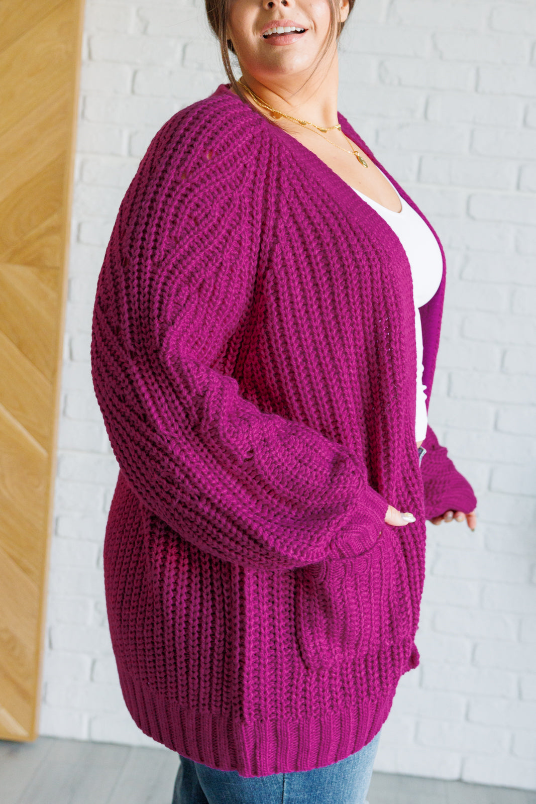 Women's long-line cardigan in the color berry sweater knit fabric with an open front, long sleeves, functional patch pockets, and exaggerated ribbed sleeve cuffs and hemline.