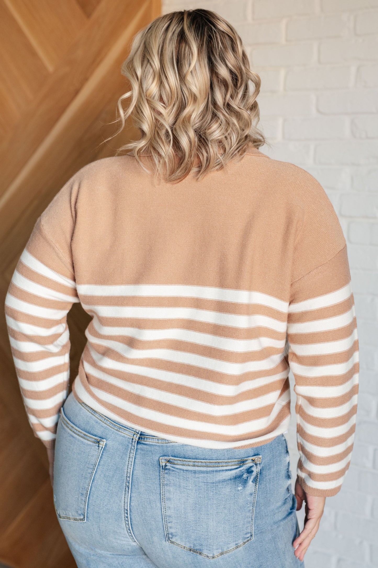 A striped midweight sweater knit in white and beige featuring a collared V-neckline, long sleeves, and a cropped length with a relaxed fit.